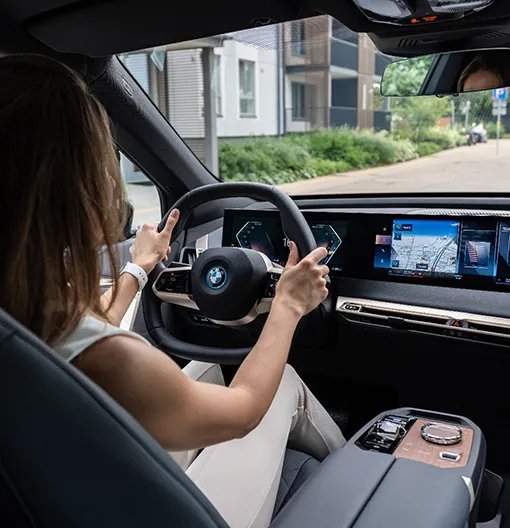Woman driving a BMW vehicle with digital dashboard and navigation system