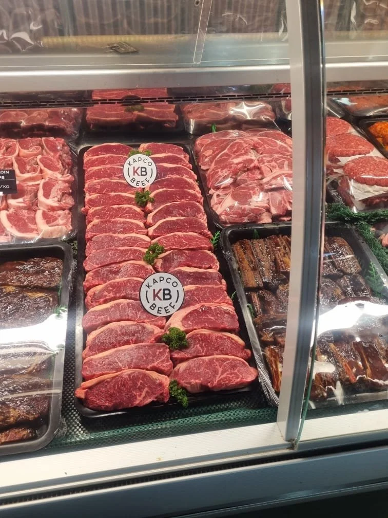 Display case with various cuts of beef, including steaks and ribs, labeled with the brand 'KB'.