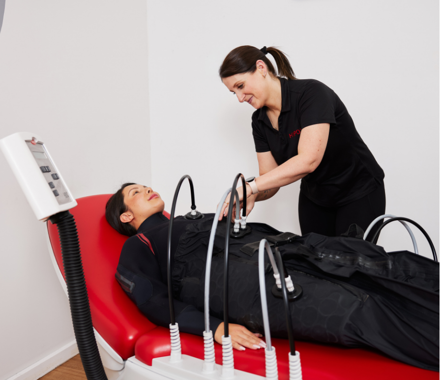 Medical professional performing a non-invasive procedure on a woman lying on a medical bed, with medical equipment attached.