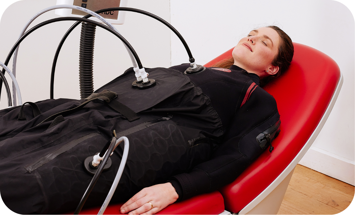 A woman lying on a medical examination chair receiving a treatment with multiple tubes attached to her chest.
