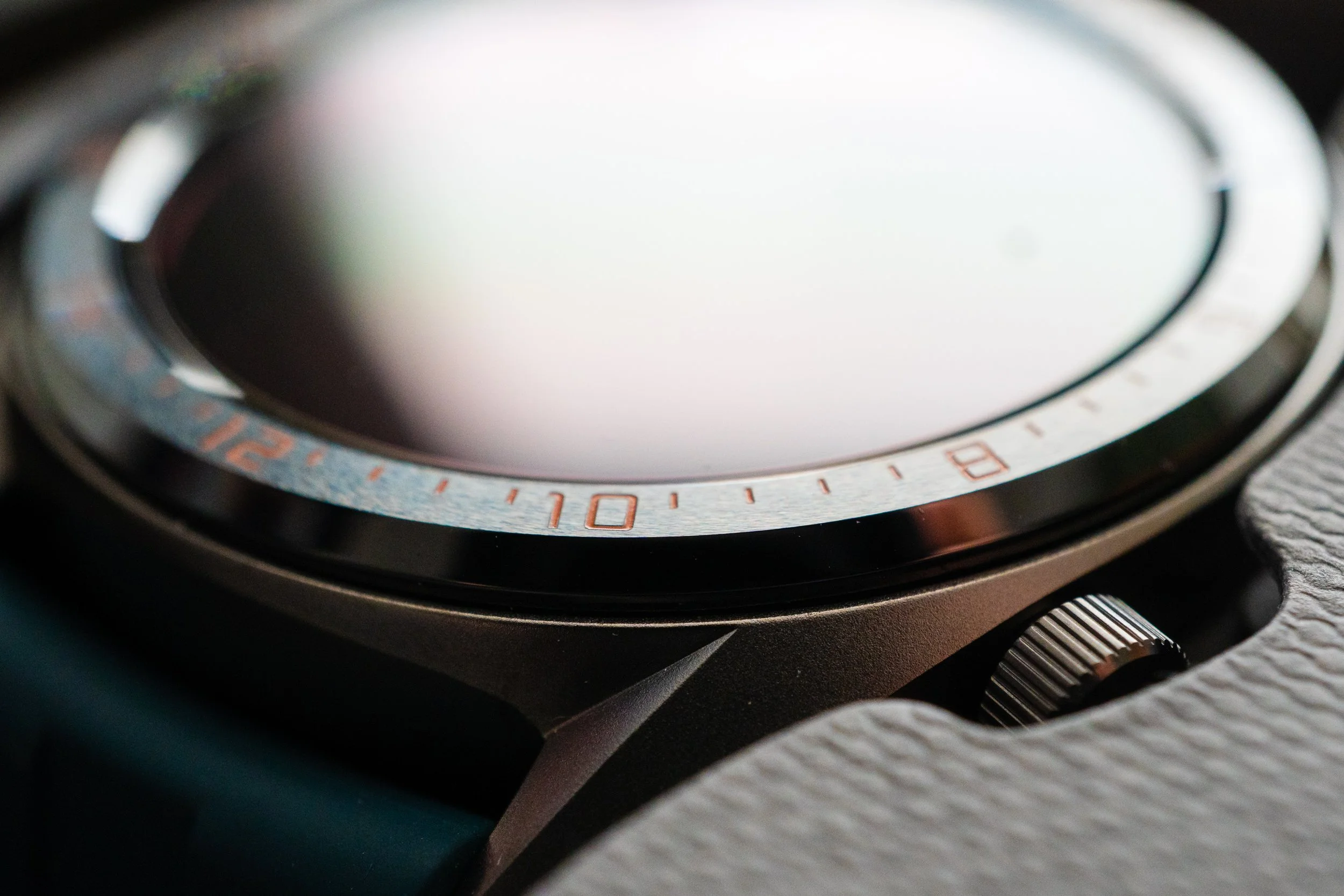 Close-up of a wristwatch with a metallic bezel and a textured strap.