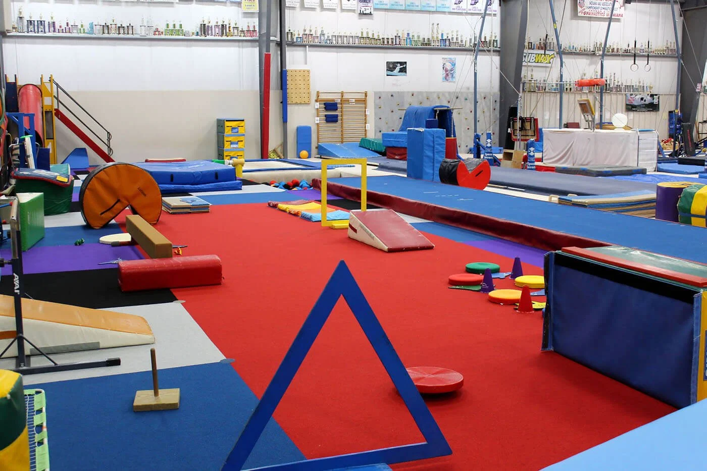 Indoor gymnastics gym with various mats, training equipment, and colorful props for training and exercises.