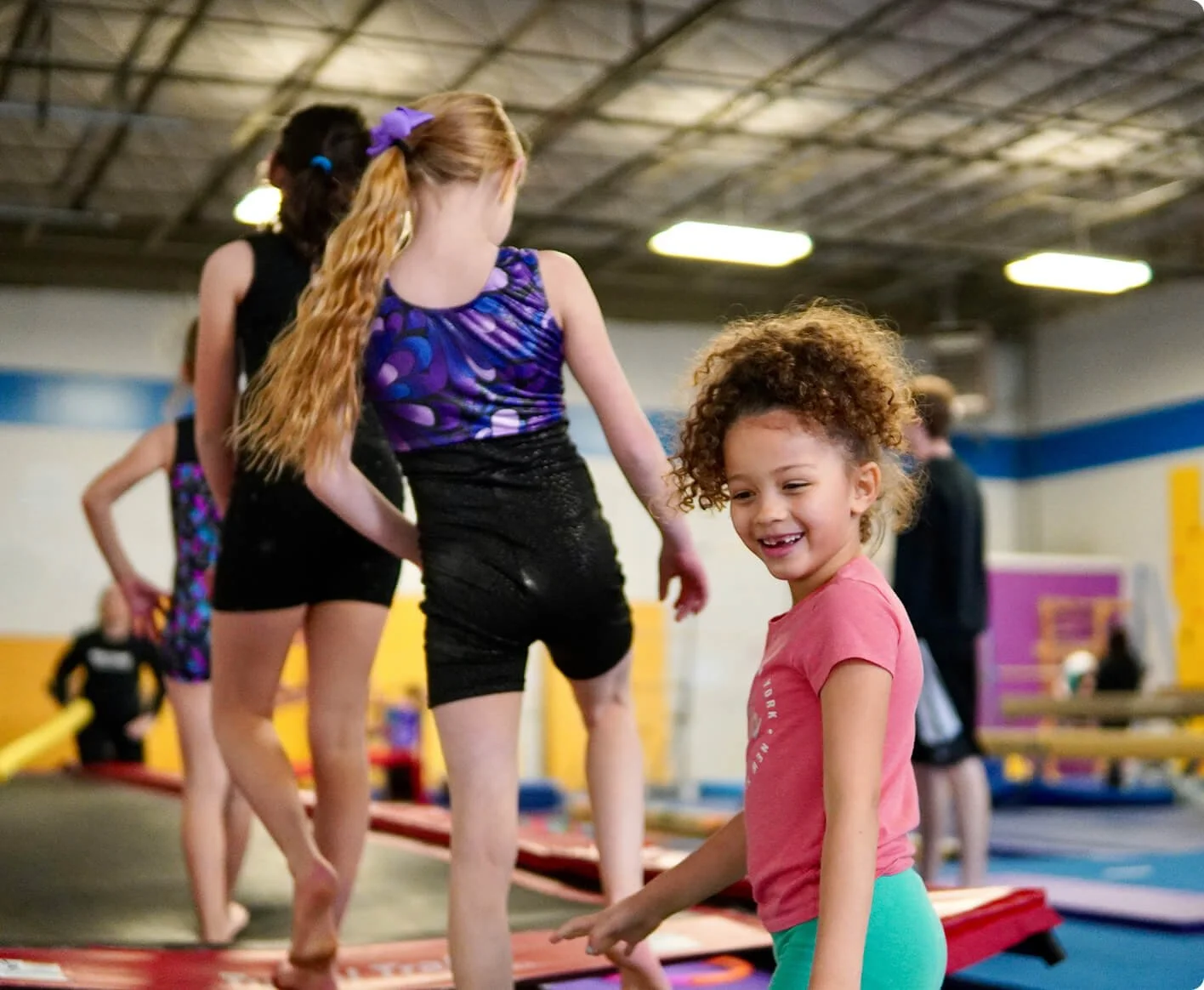 Children practicing gymnastics on trampolines in an indoor gym.