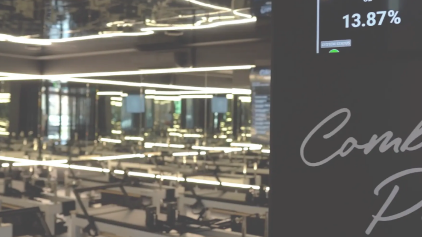 Interior of a modern space with reflective surfaces and bright lighting, partly showing a digital display reading "13.87%" and "System Status" along with partial cursive text.