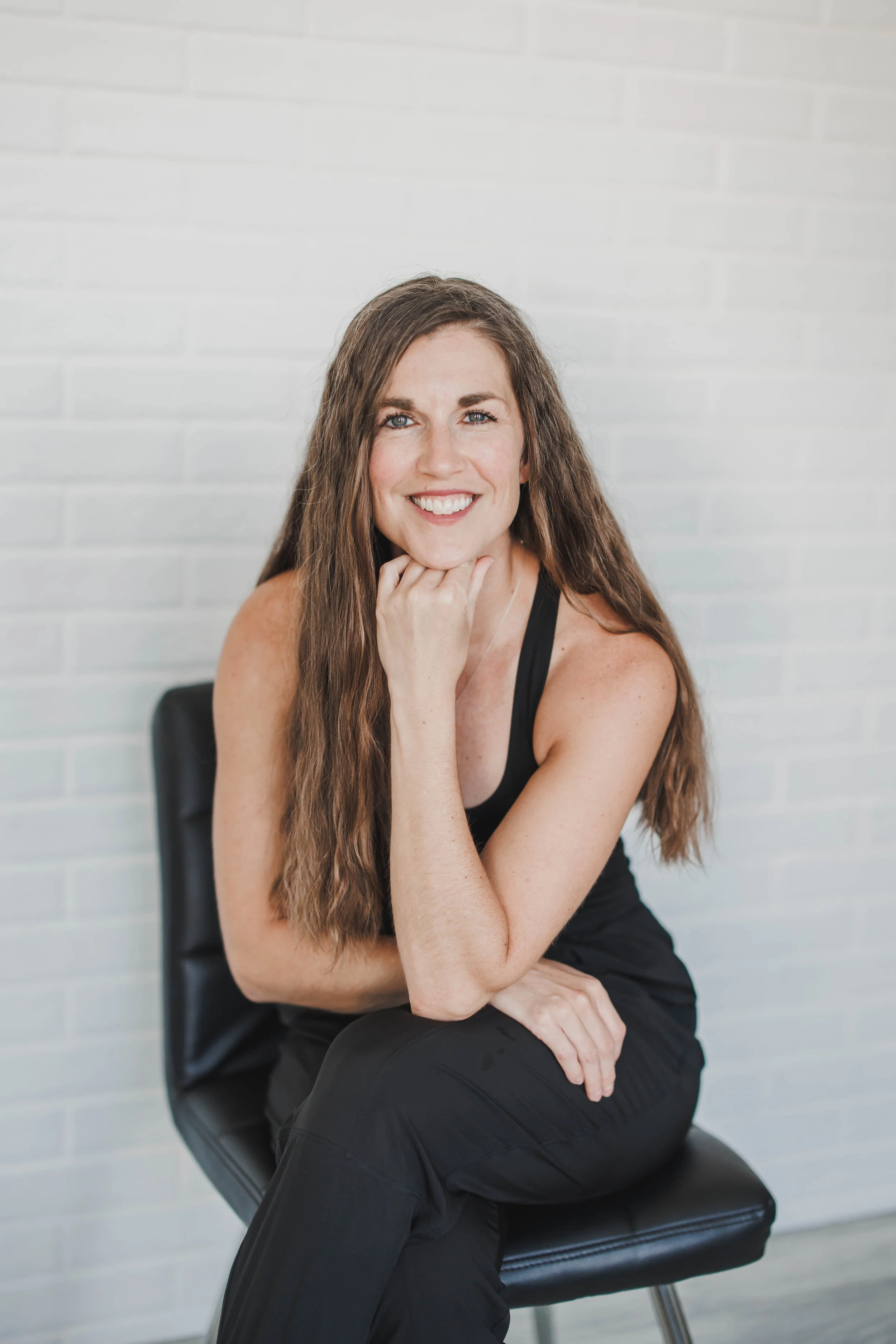 Andrea Carow smiling, seated with her hand beneath her chin
