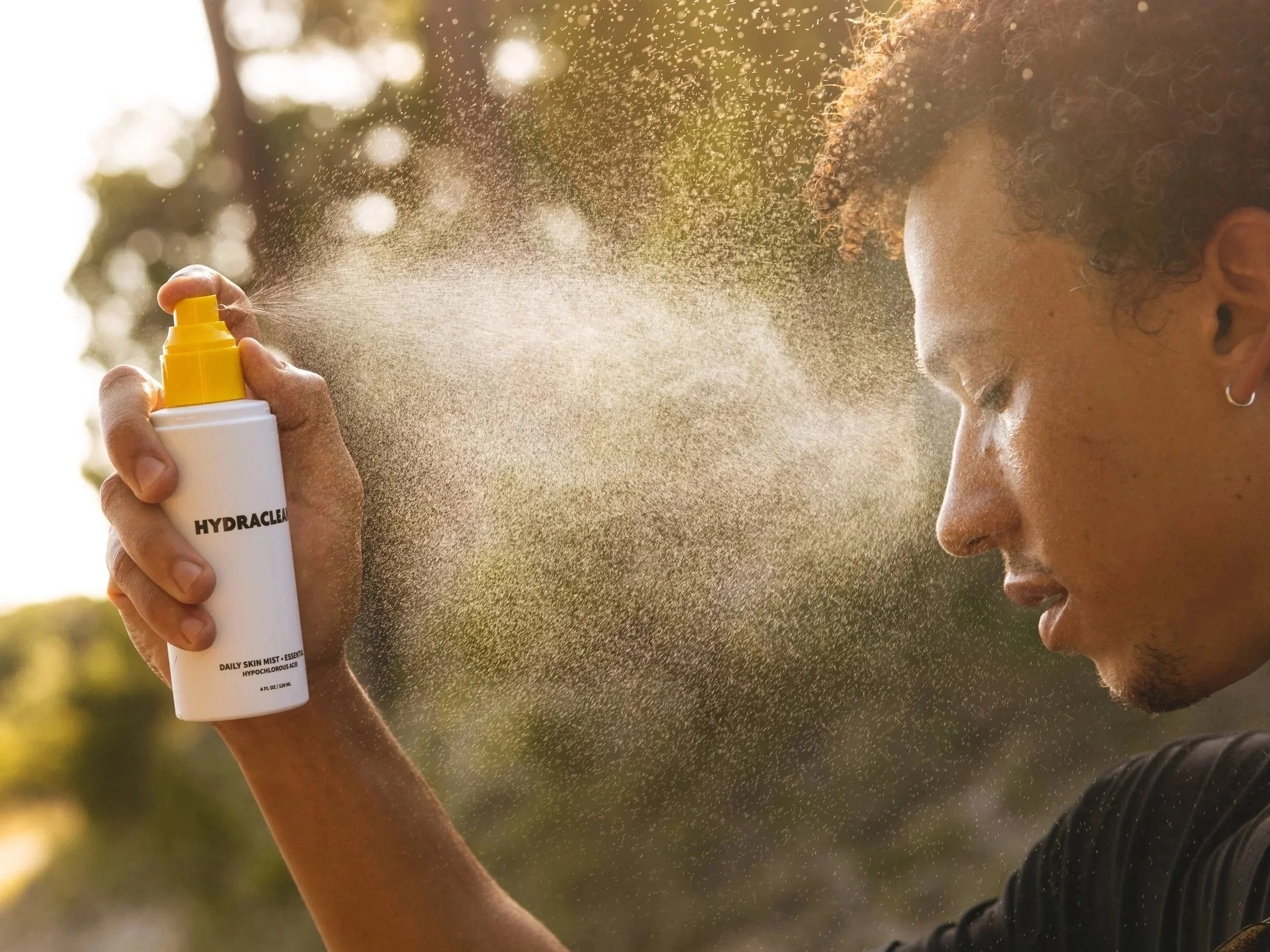 Man applying HYDRACLEAN Daily Skin Mist to his face after movement
