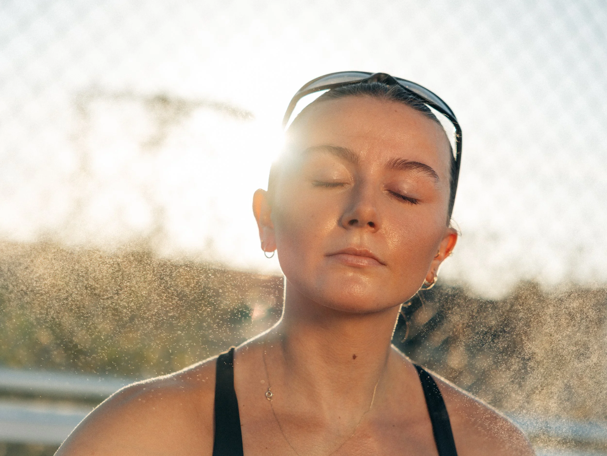 Woman applying HYDRACLEAN Daily Skin Mist after running on a track