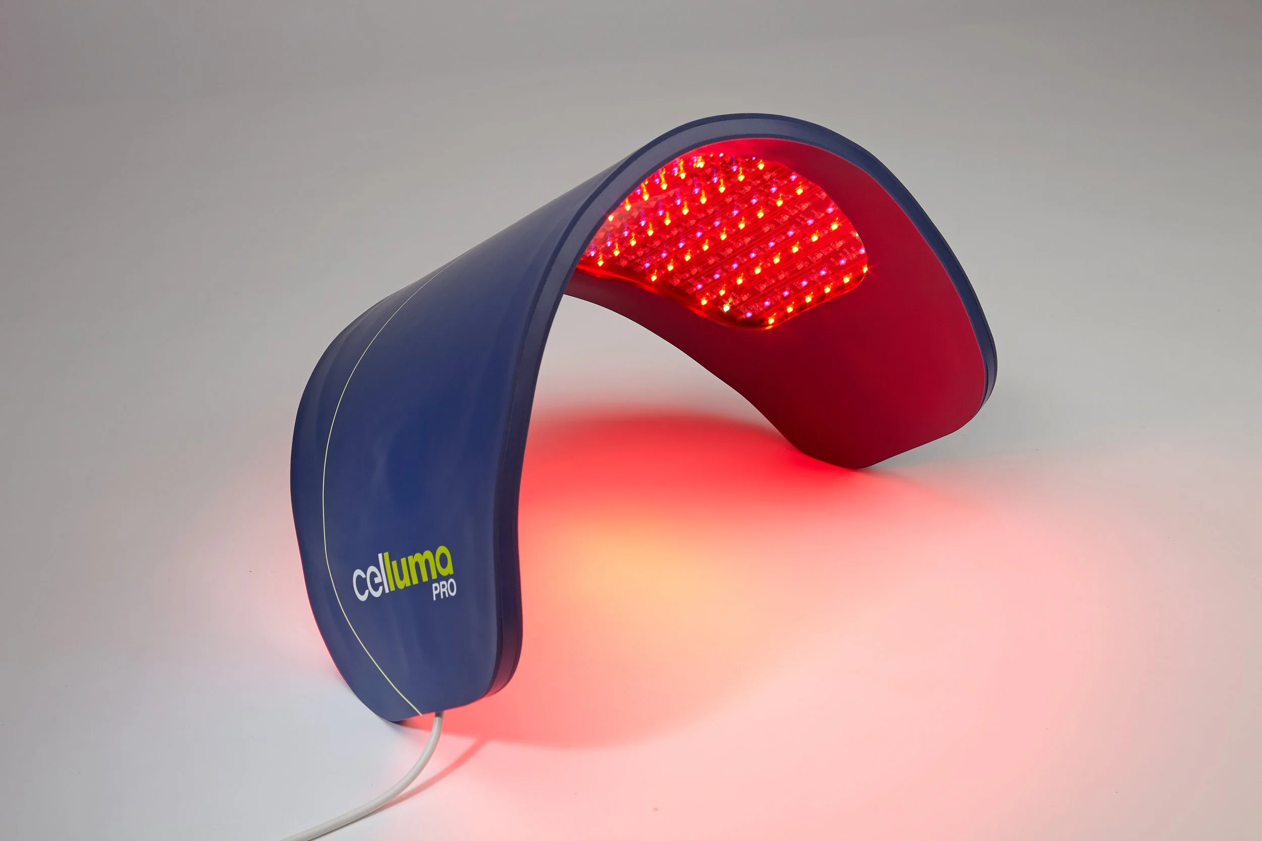A blue LED light therapy device labeled 'celluma PRO' with a curved design, emitting red light.
