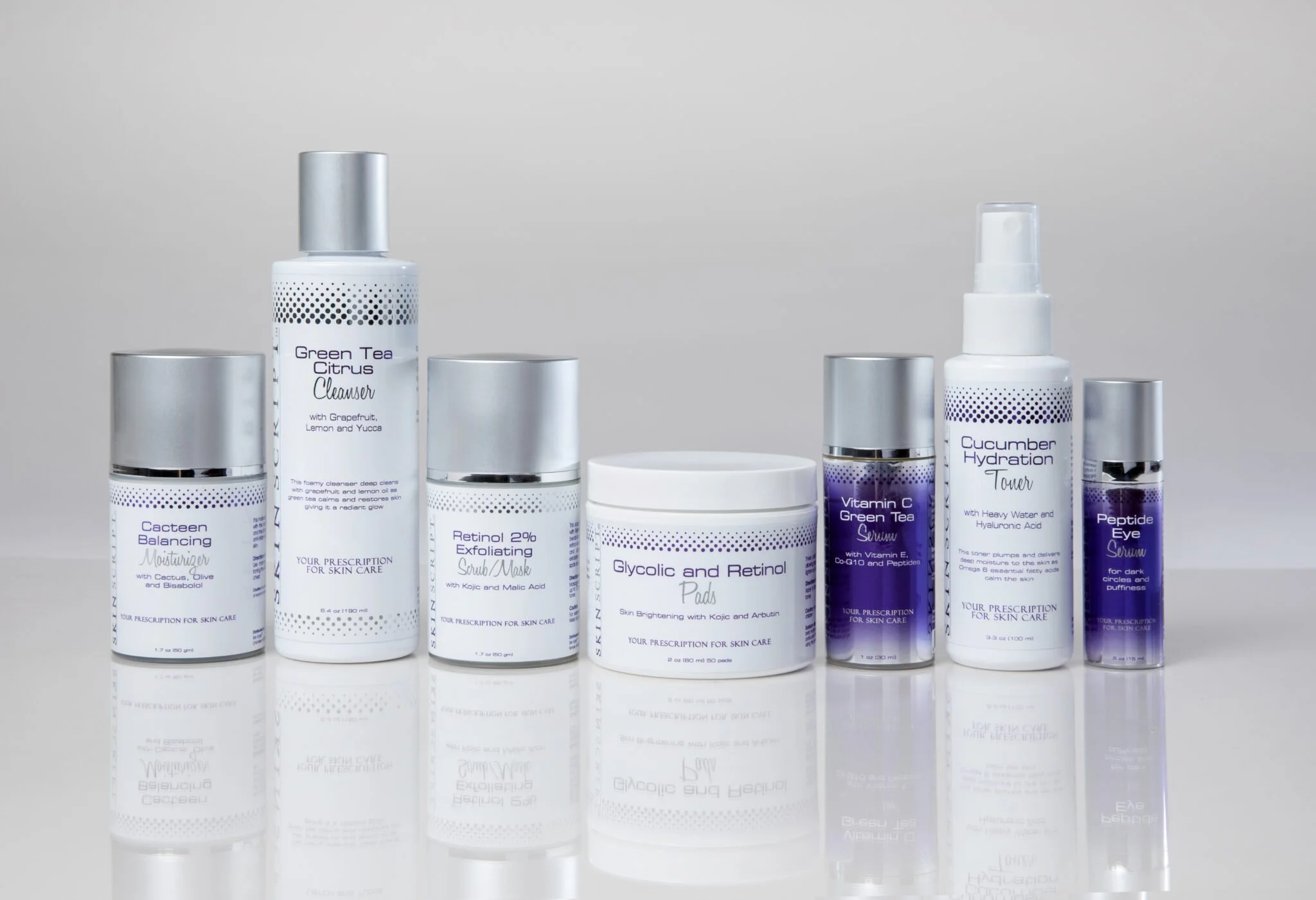 Collection of skincare products including cleansers, serums, exfoliants, and pads with white and purple packaging, some with metallic caps or spray tops, displayed on a reflective surface.