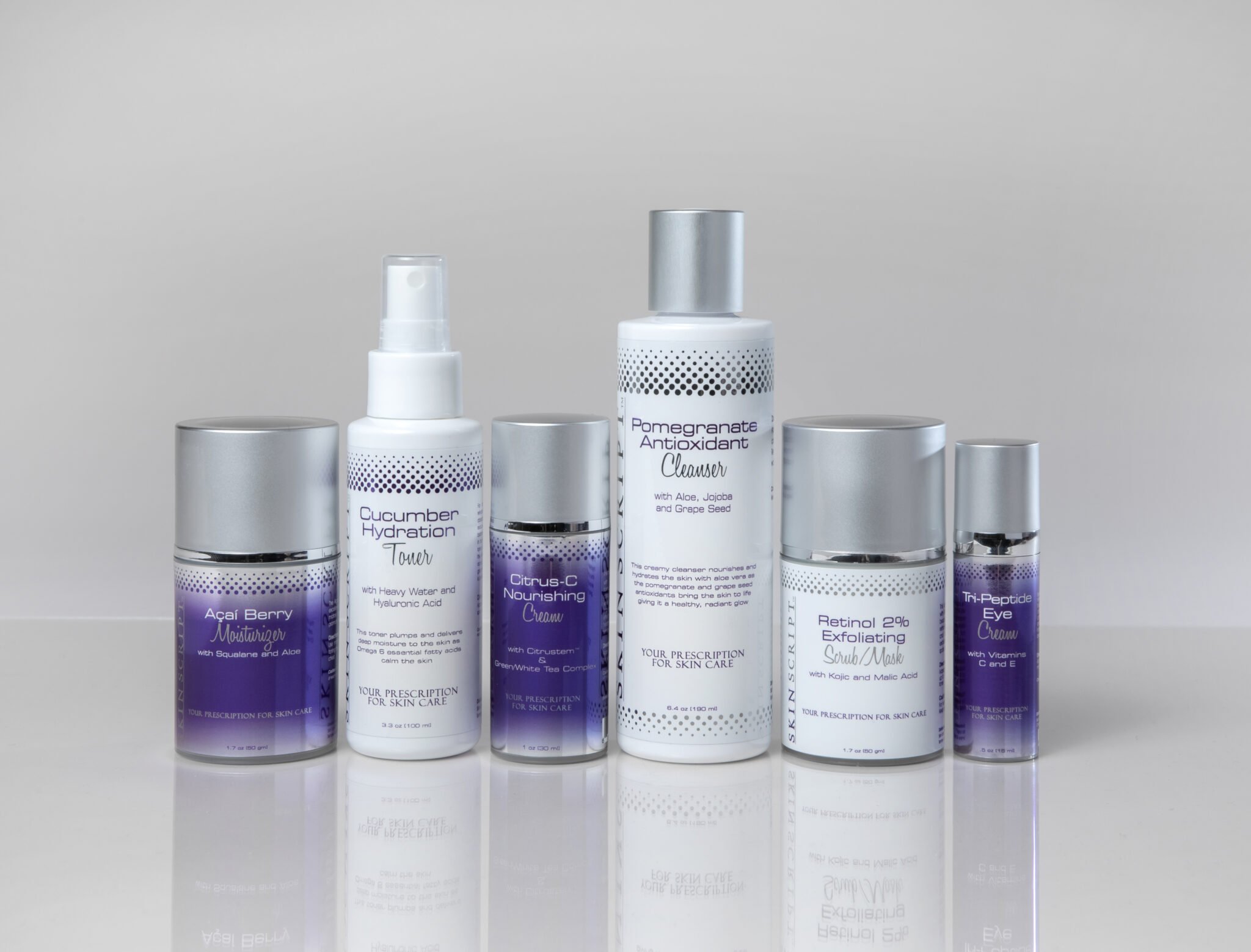 Collection of six skincare products including moisturizer, toner, nourishing cream, cleanser, scrub mask, and eye cream with purple and white packaging on a reflective white surface.