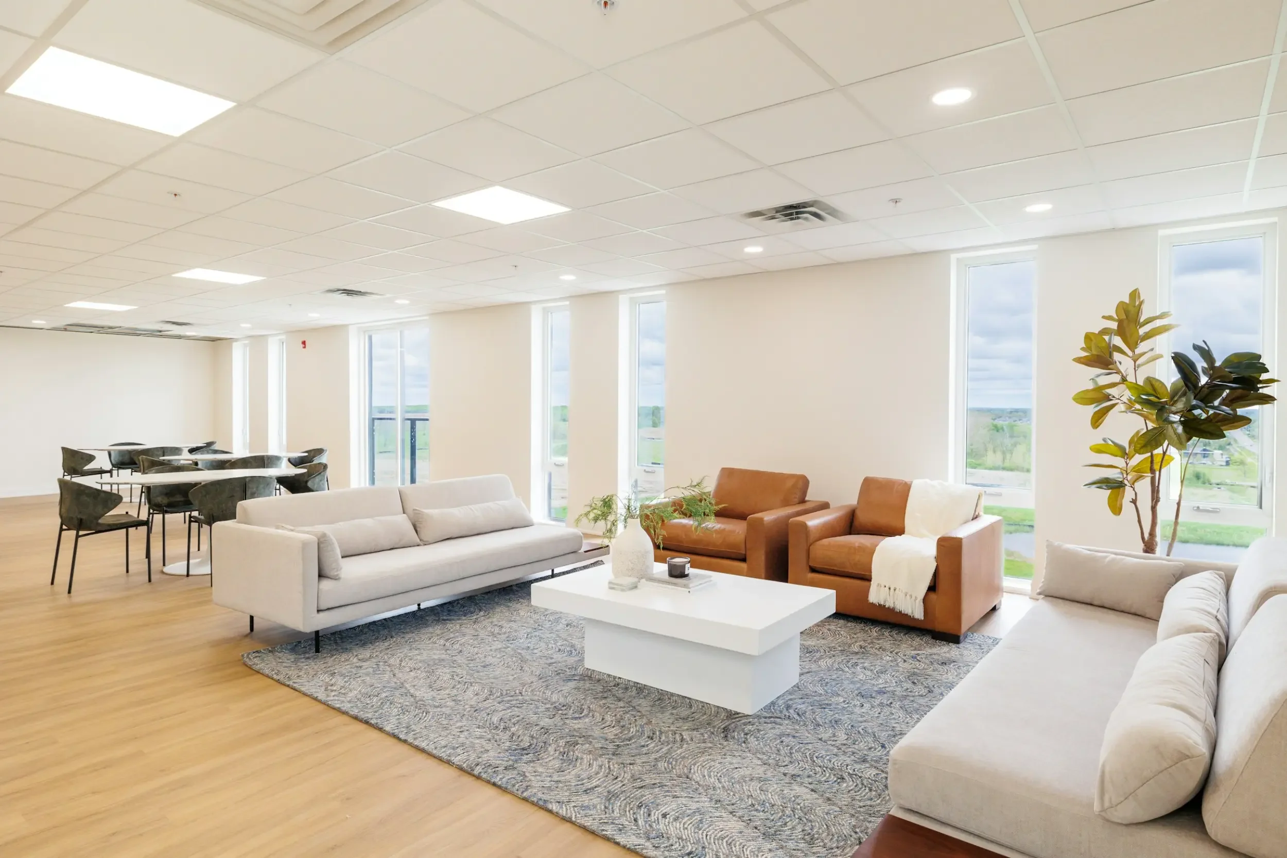 Bright, modern lounge with tan armchairs, beige sofas, a white coffee table—perfect for spaces maintained by commercial cleaning services.