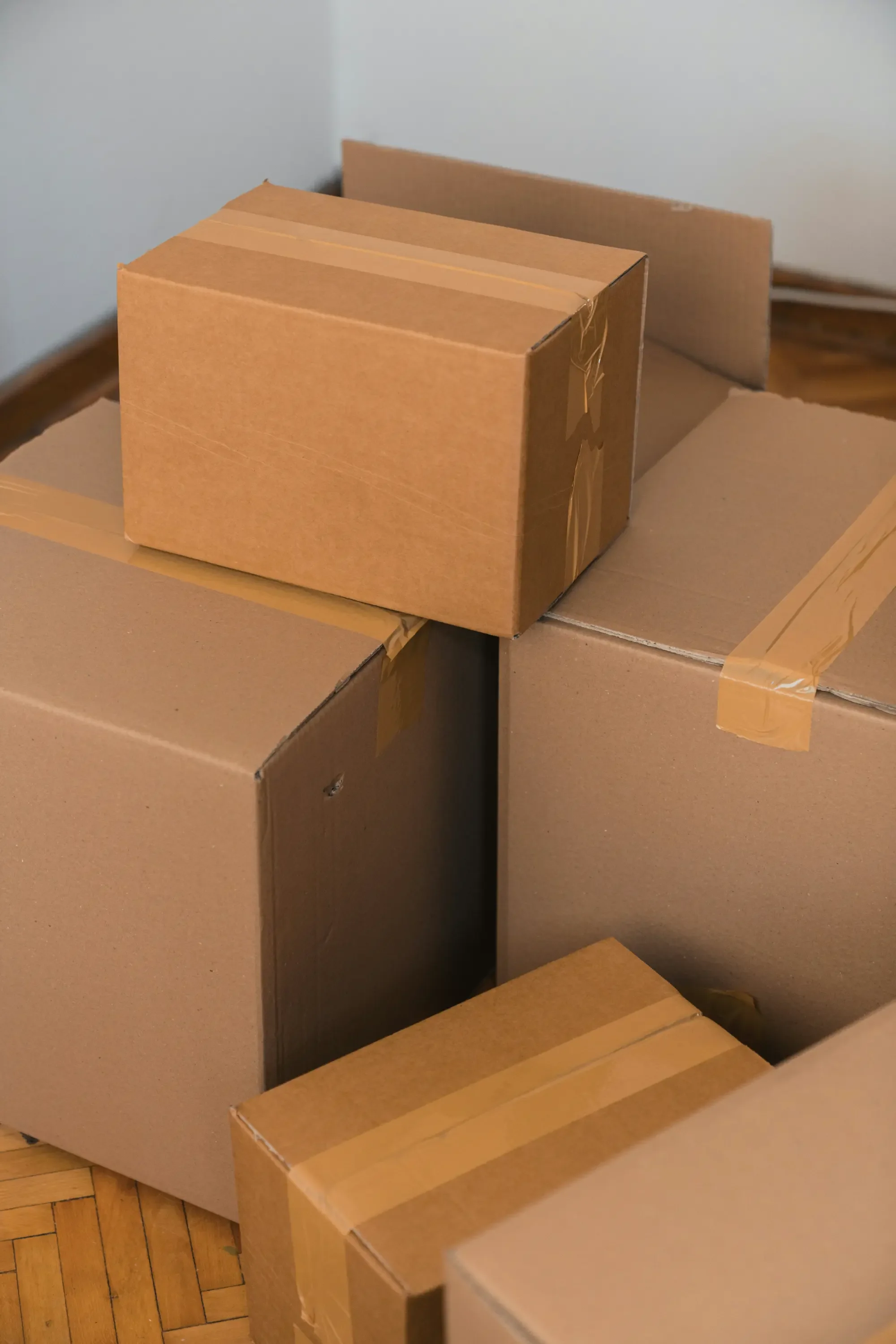 brown generic moving boxes sitting on a wooden floor of an empty room before or after a move in out clean service
