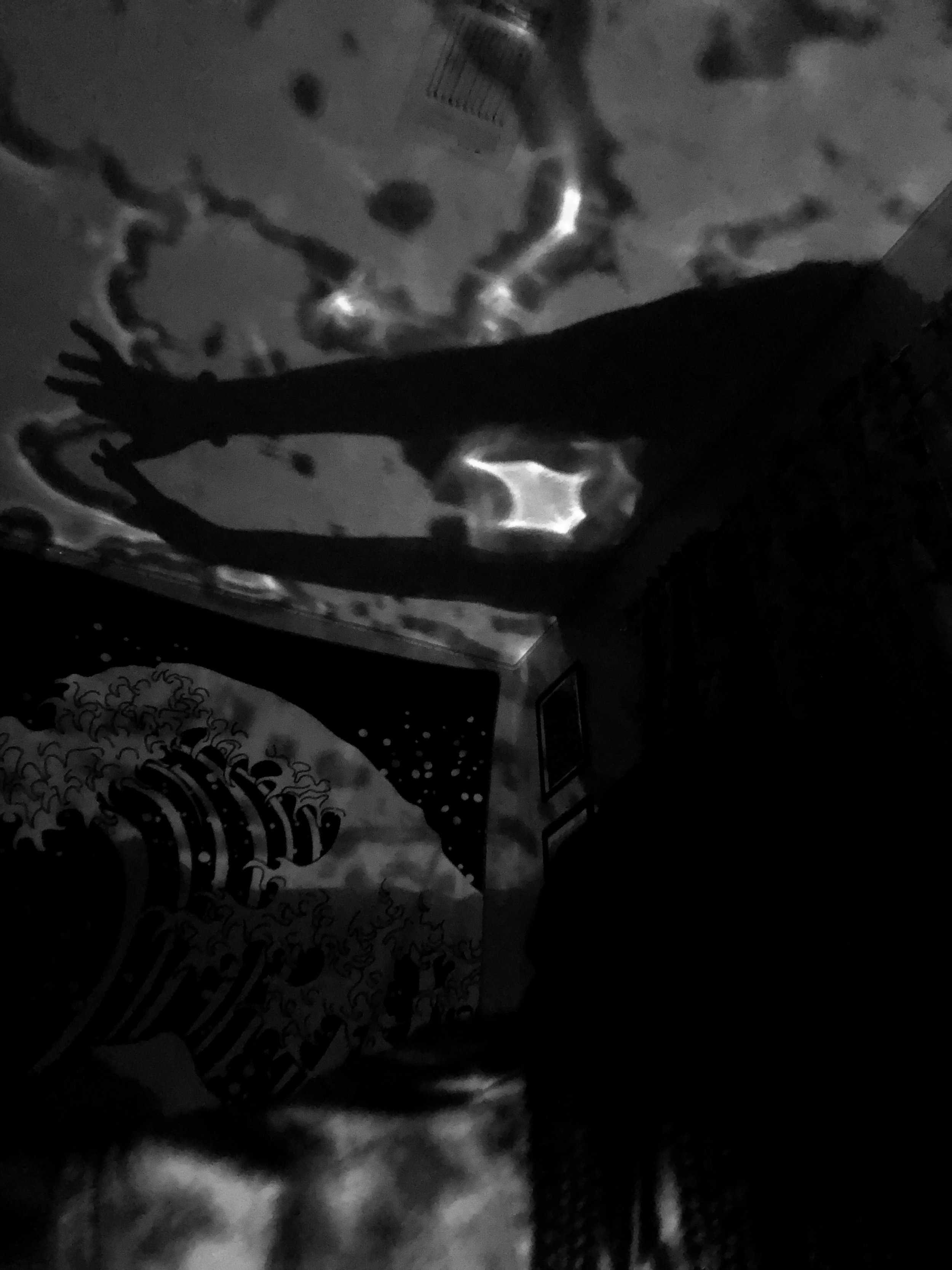 A silhouette of a person reaching out toward a projected ocean wave on the wall, with a starry sky and wave pattern in the background.