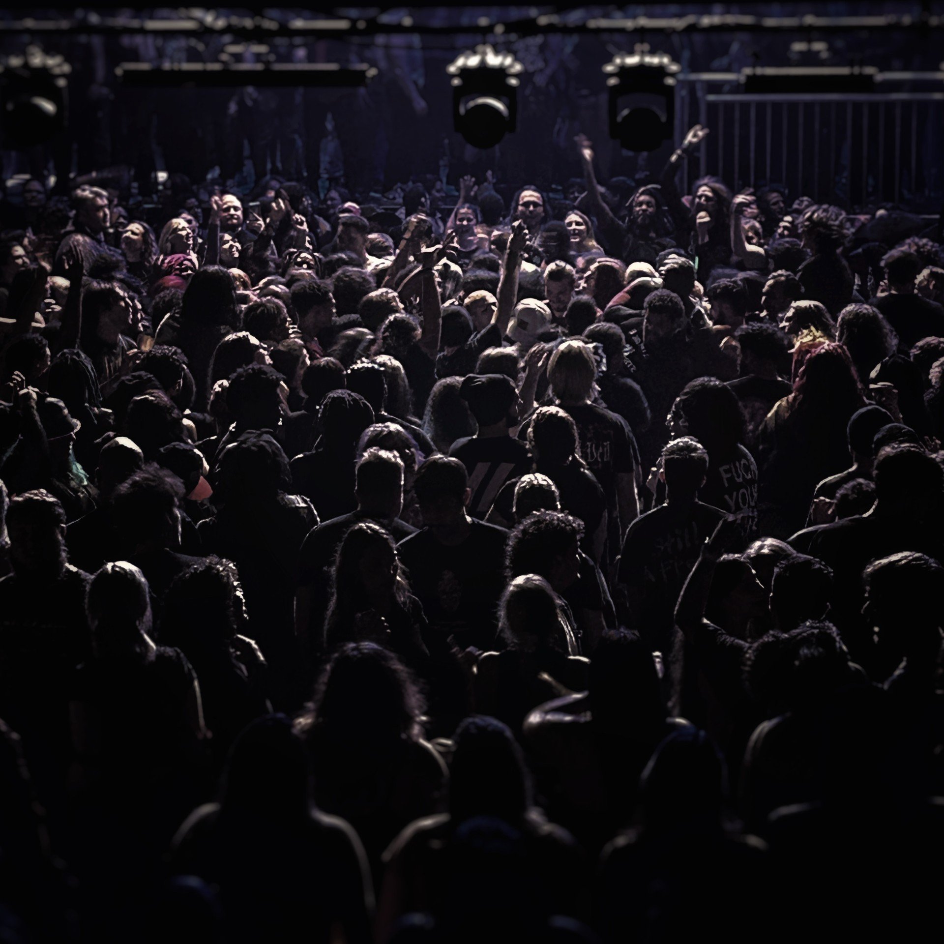 A large crowd of people at a concert or event, with some raising their arms, in a dimly lit environment. Atlanta Masquerade concert. Atl masquerade photography.