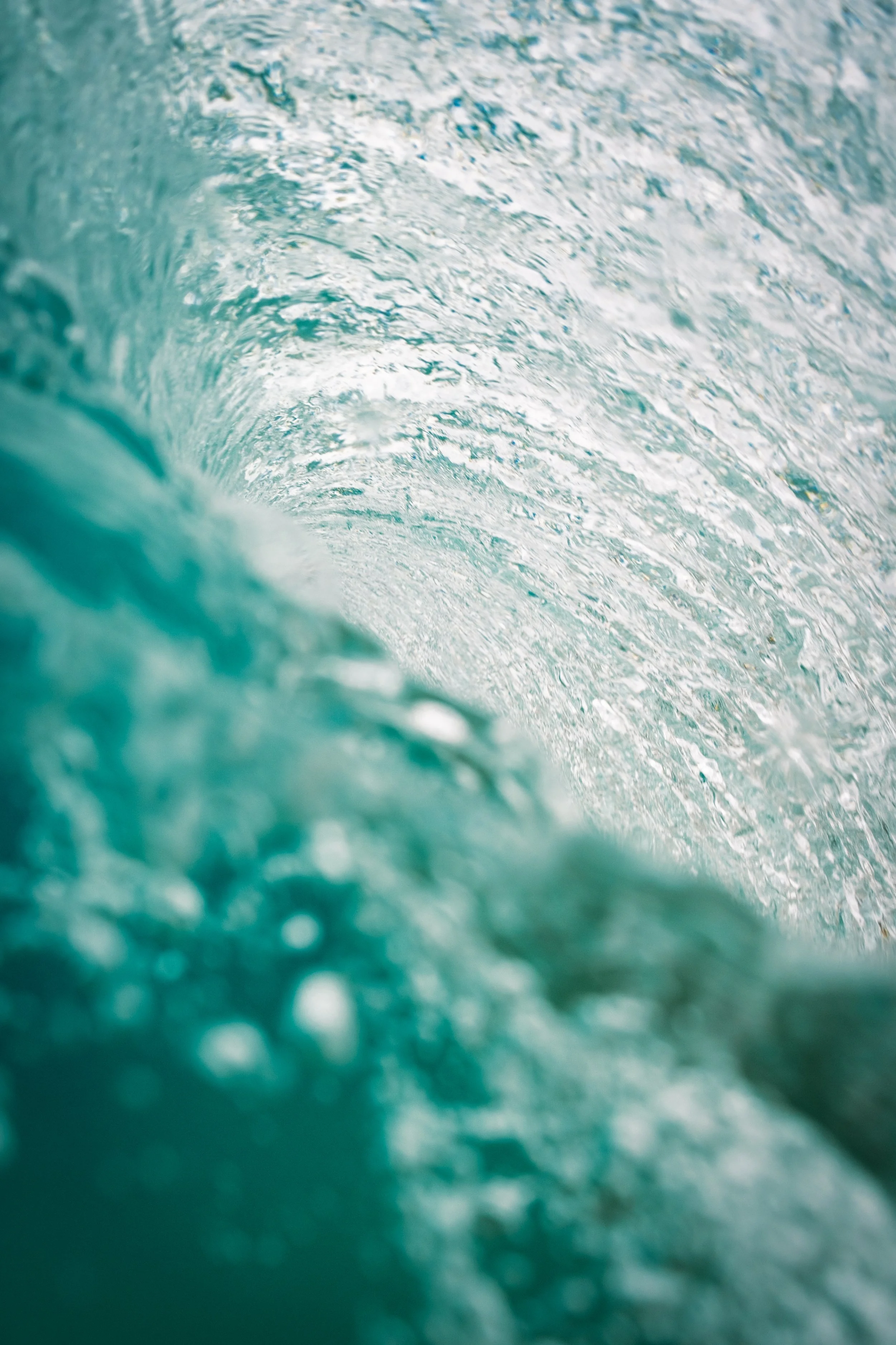 A photo taken from inside a wave, showing the crest and churning water with foam.