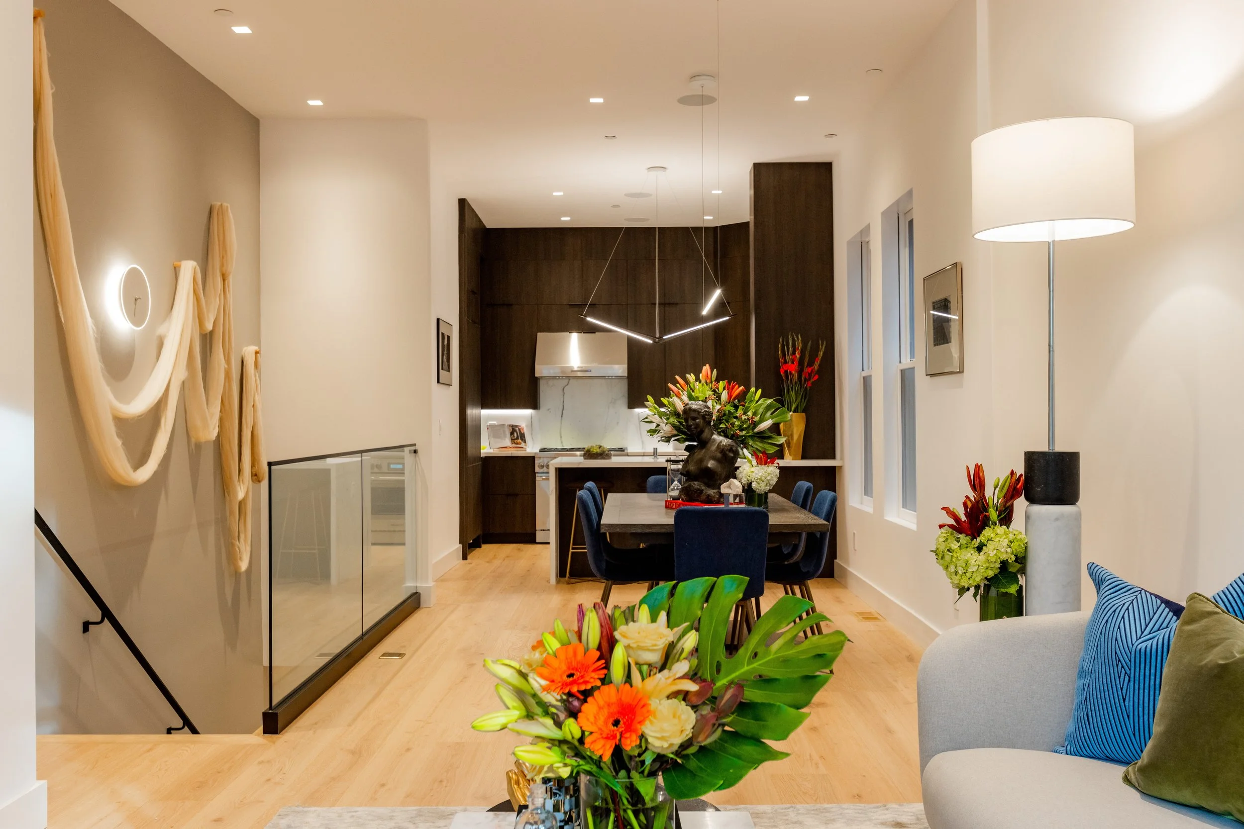 A modern, open-concept dining and kitchen area with flowers, a sculpture, and contemporary decor.