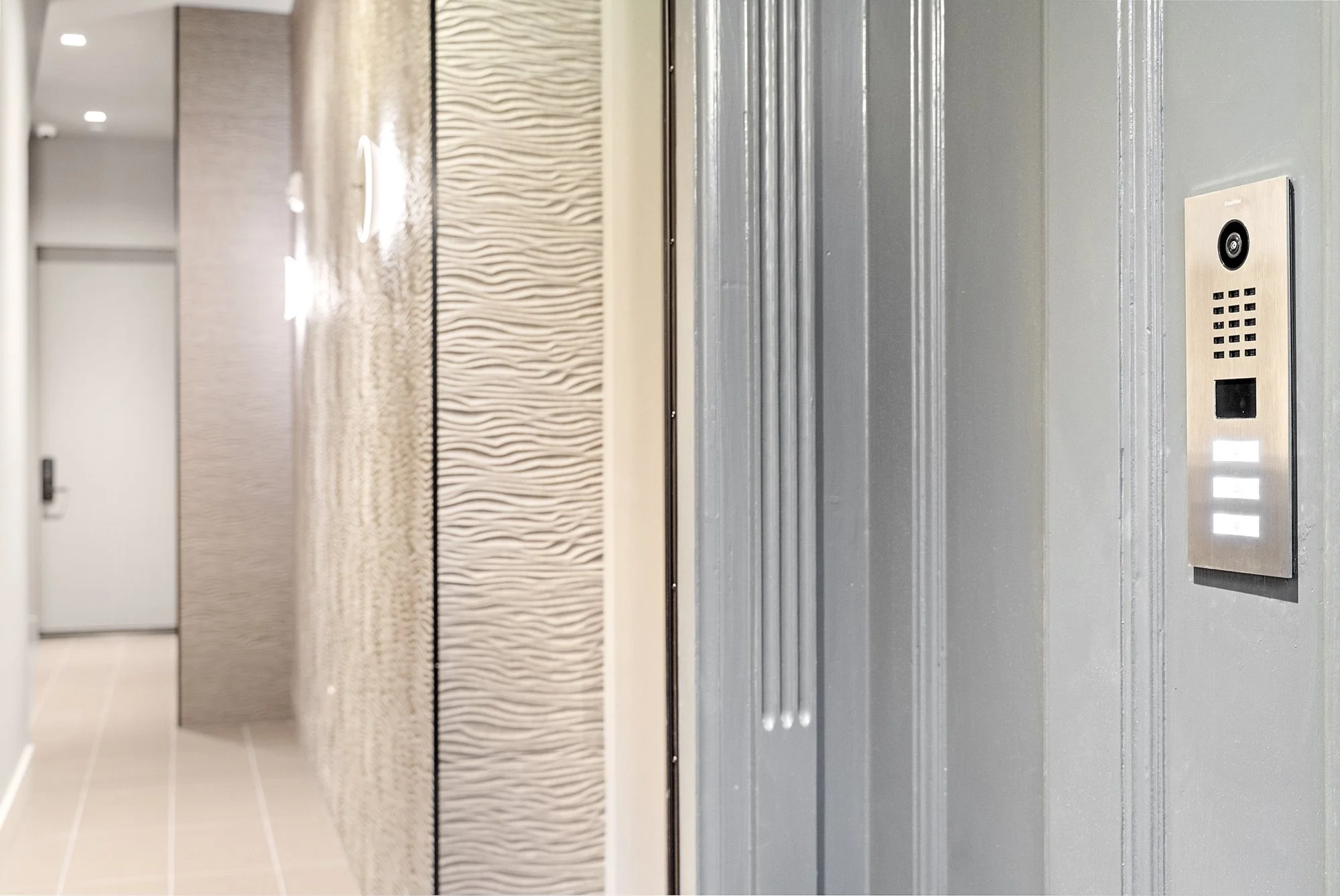 Elevator control panel with buttons and camera on a wall inside a modern building.