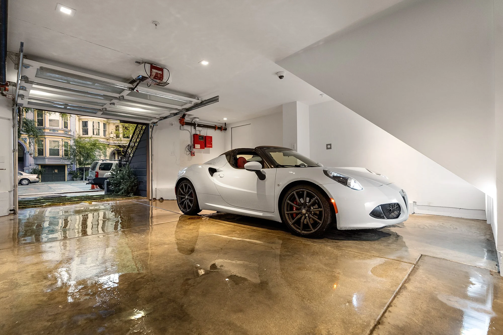 White sports car with black wheels parked inside a clean garage.