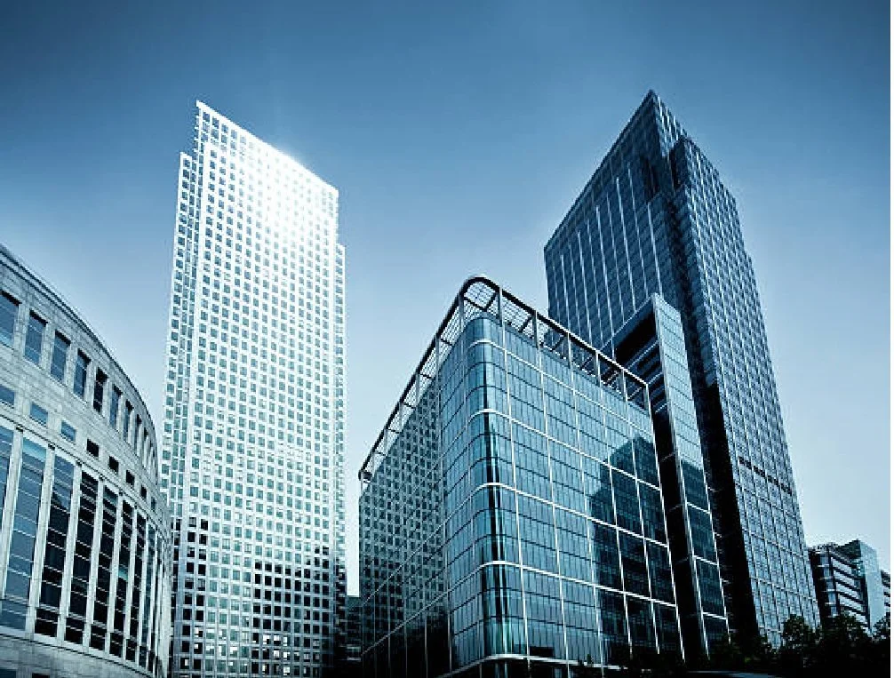 Modern skyscrapers in a city with glass facades reflecting the sky and surroundings.
