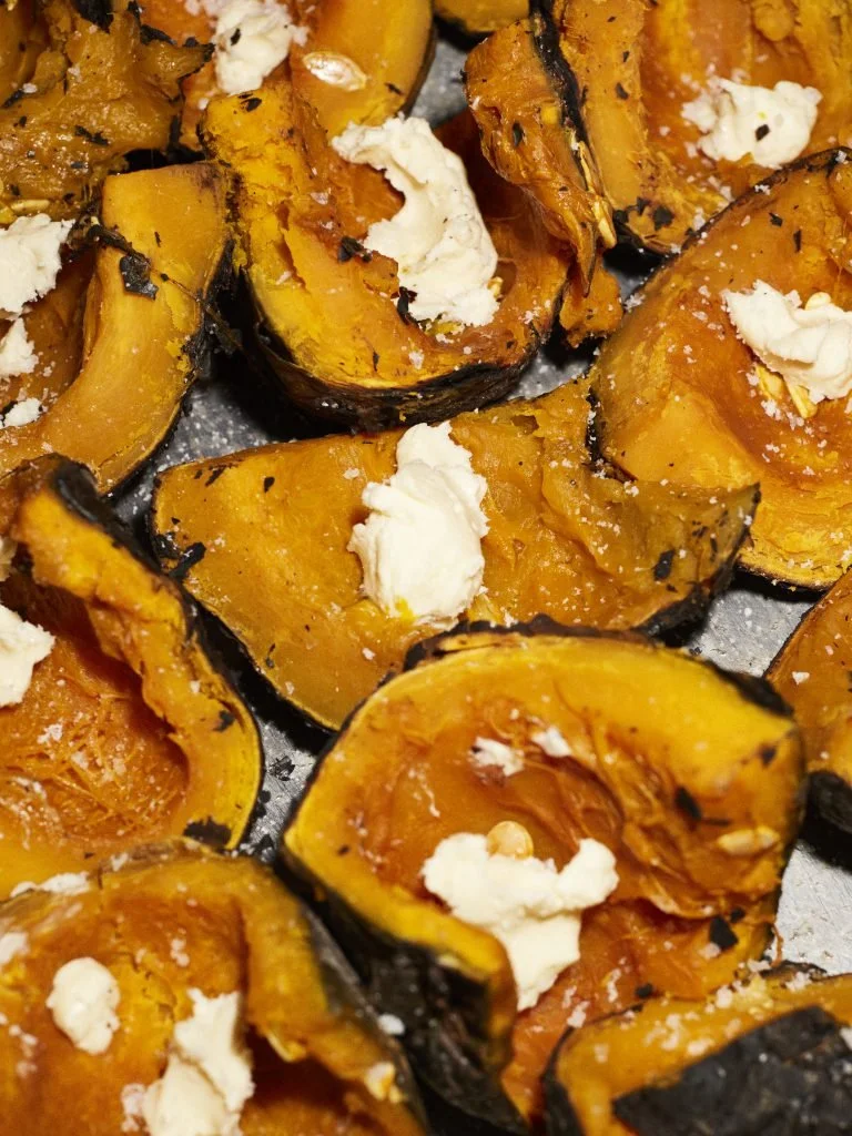 Roasted butternut squash halves topped with crumbled feta cheese.