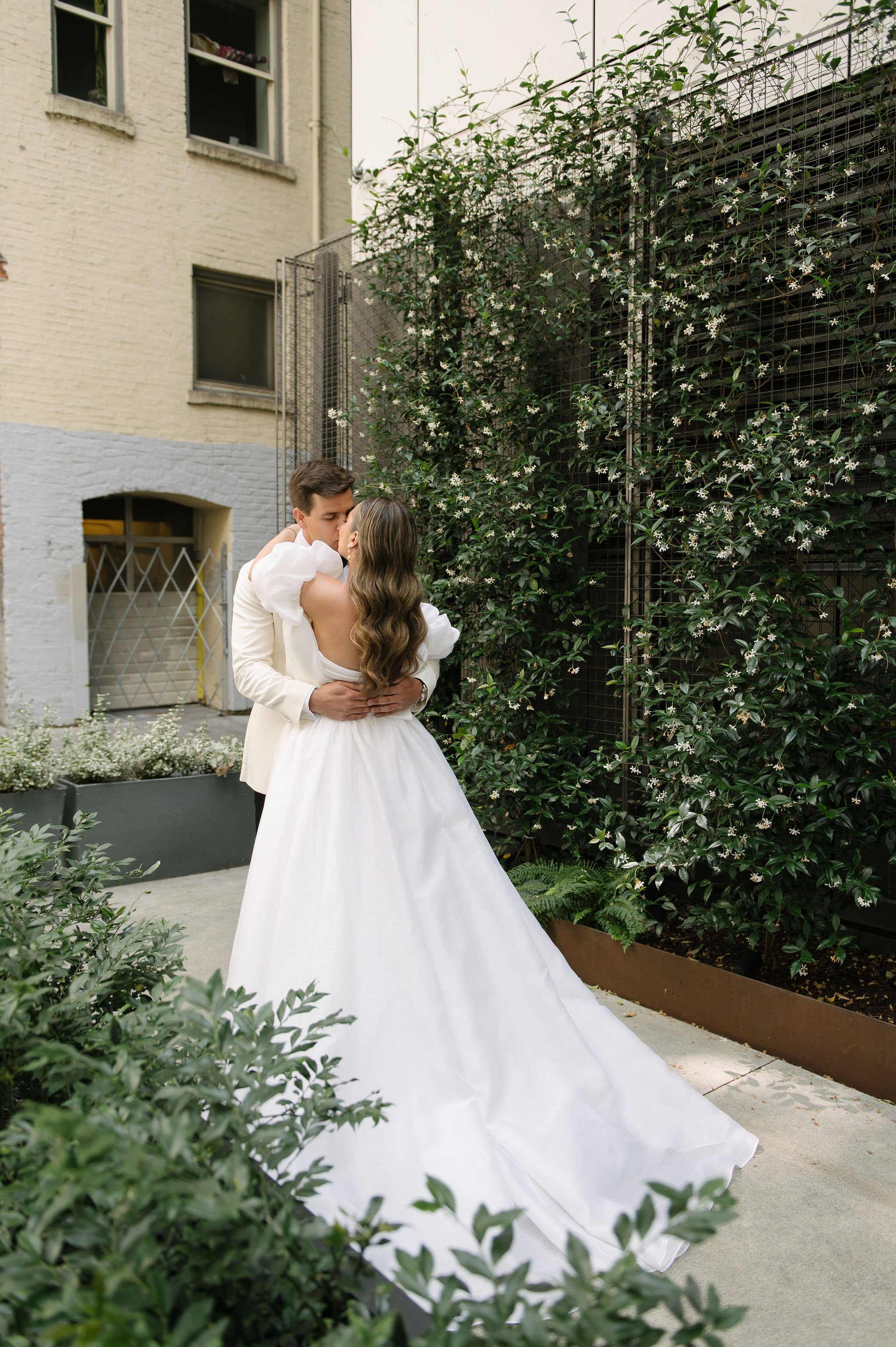 A couple in wedding attire embracing and about to kiss outdoors surrounded by greenery and flowers, with buildings in the background.
Makeup Katya
Hair Meghhann
Venue Admiral's house
Planner Amber Sooter
Photographer Juliet and Liz