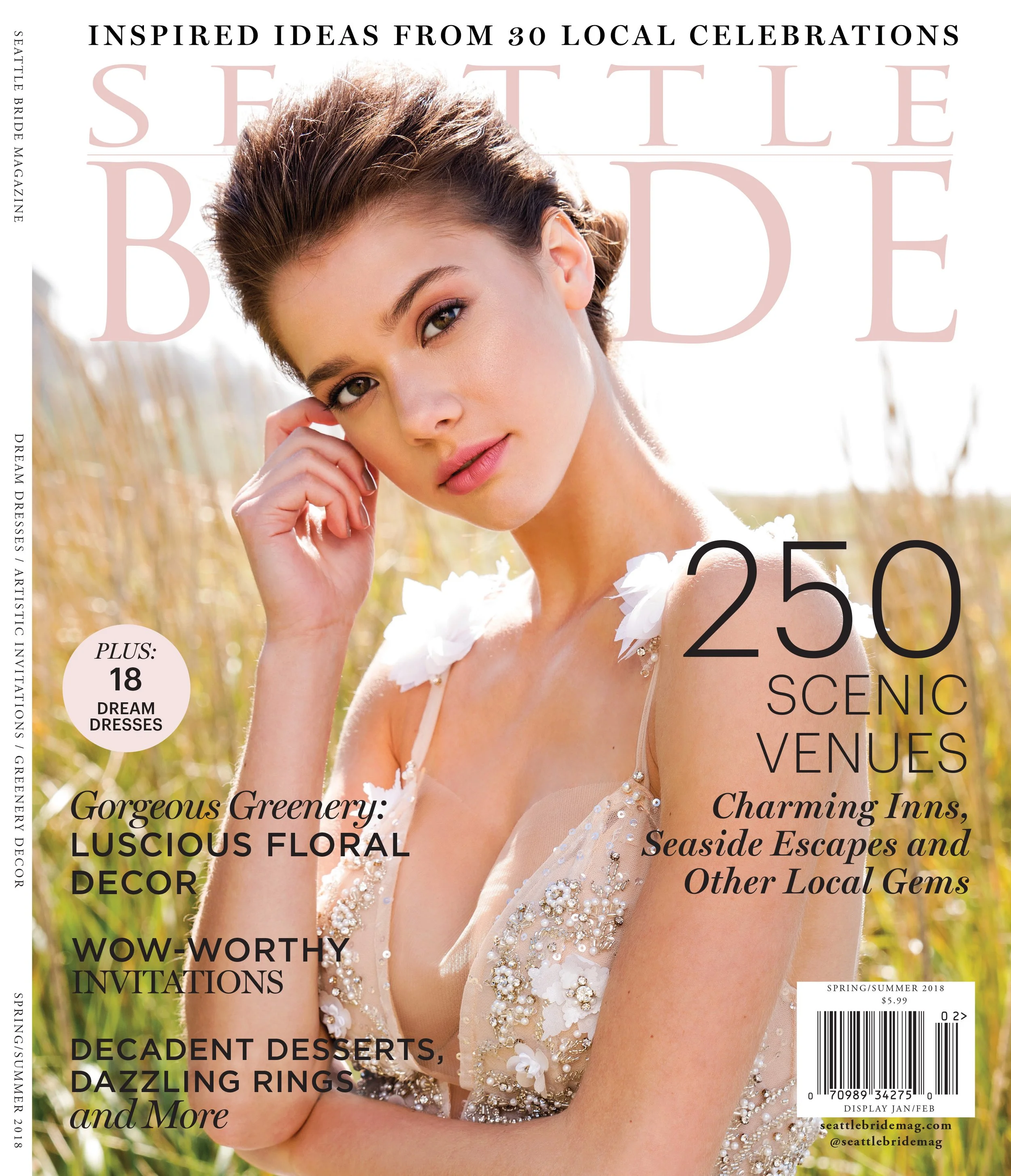 A woman with short brown hair and light skin, wearing a dress with floral embellishments, is looking directly at the camera. She is outdoors with tall grass in the background, and the sunlight highlights her face.