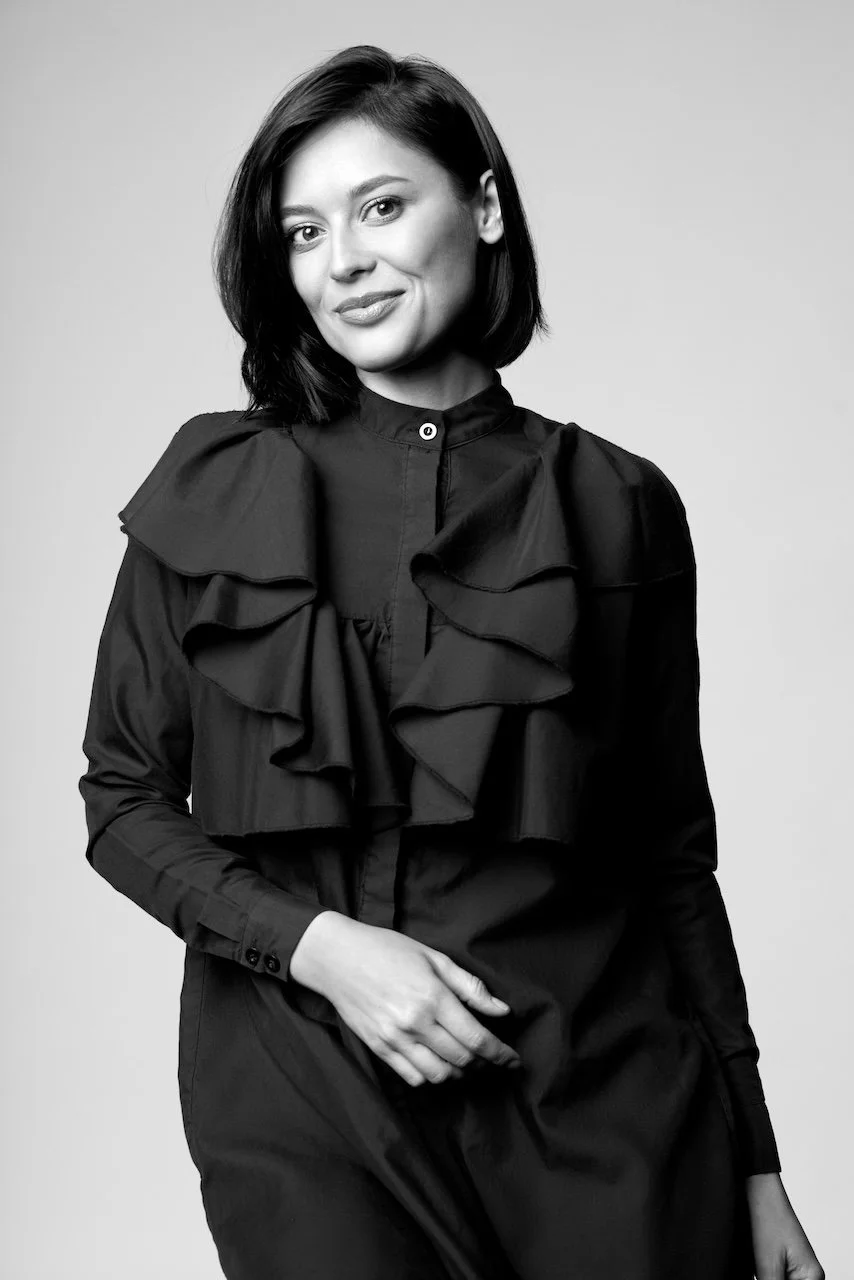 Black and white portrait of a woman with short, dark hair, wearing a dark blouse with ruffled details on the front.