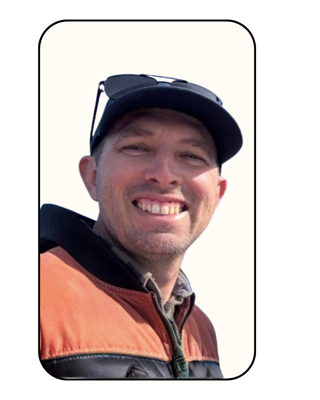 Smiling man wearing a cap, sunglasses on top, and a life jacket.