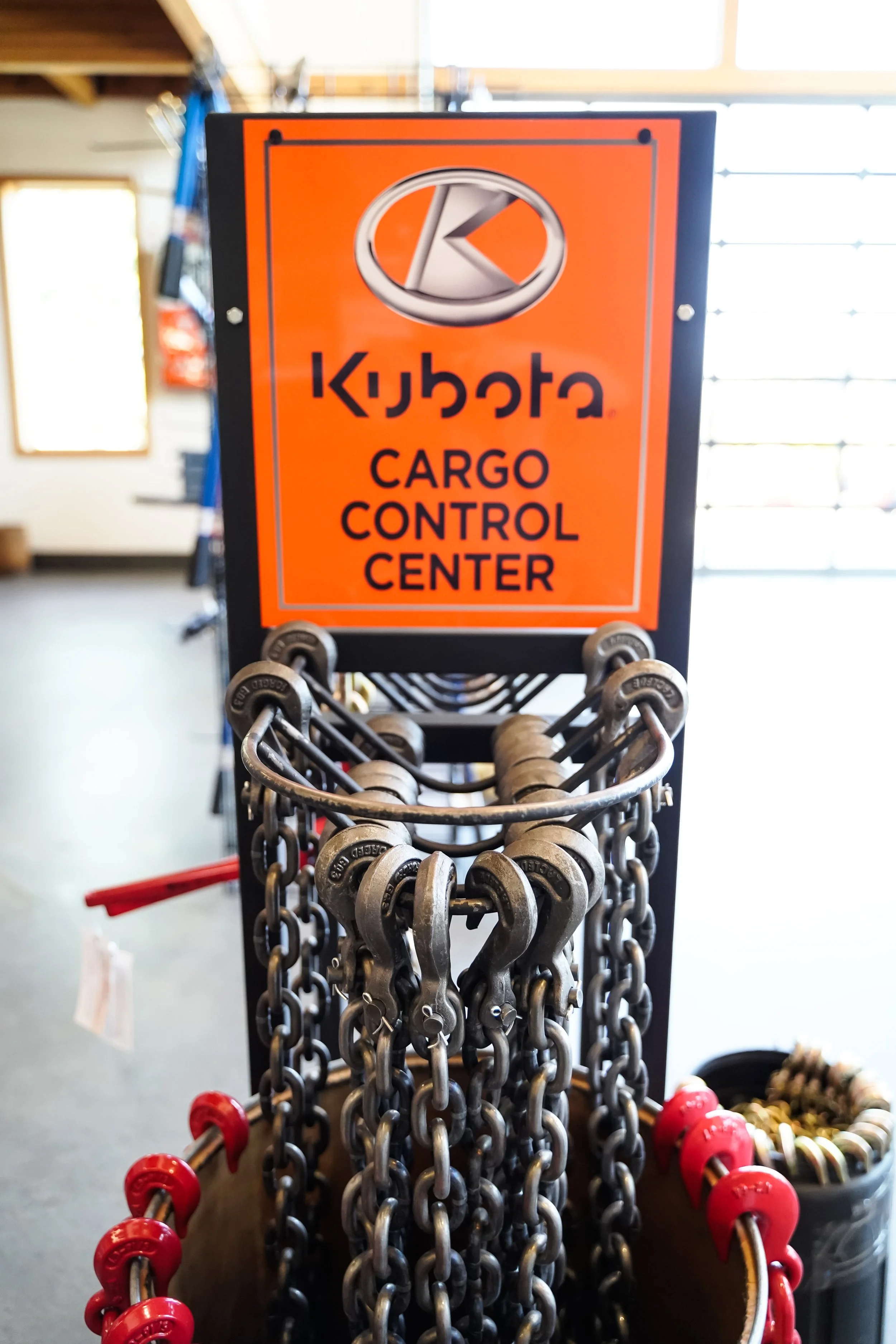 A sign reading "Kubota Cargo Control Center" hanging above chains and hooks in a store.