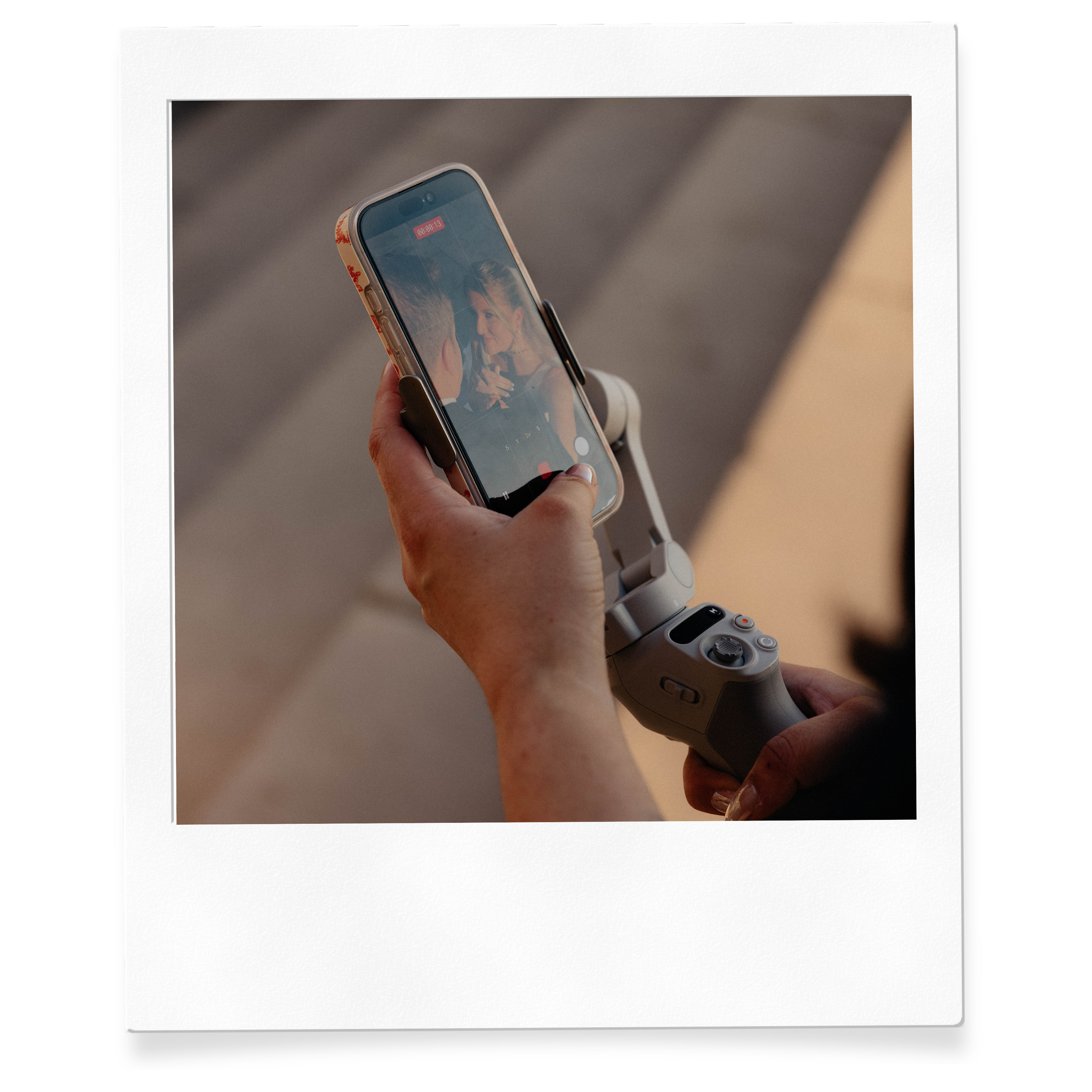Close-up of a person holding a smartphone displaying a photo of two women and some text at the top.