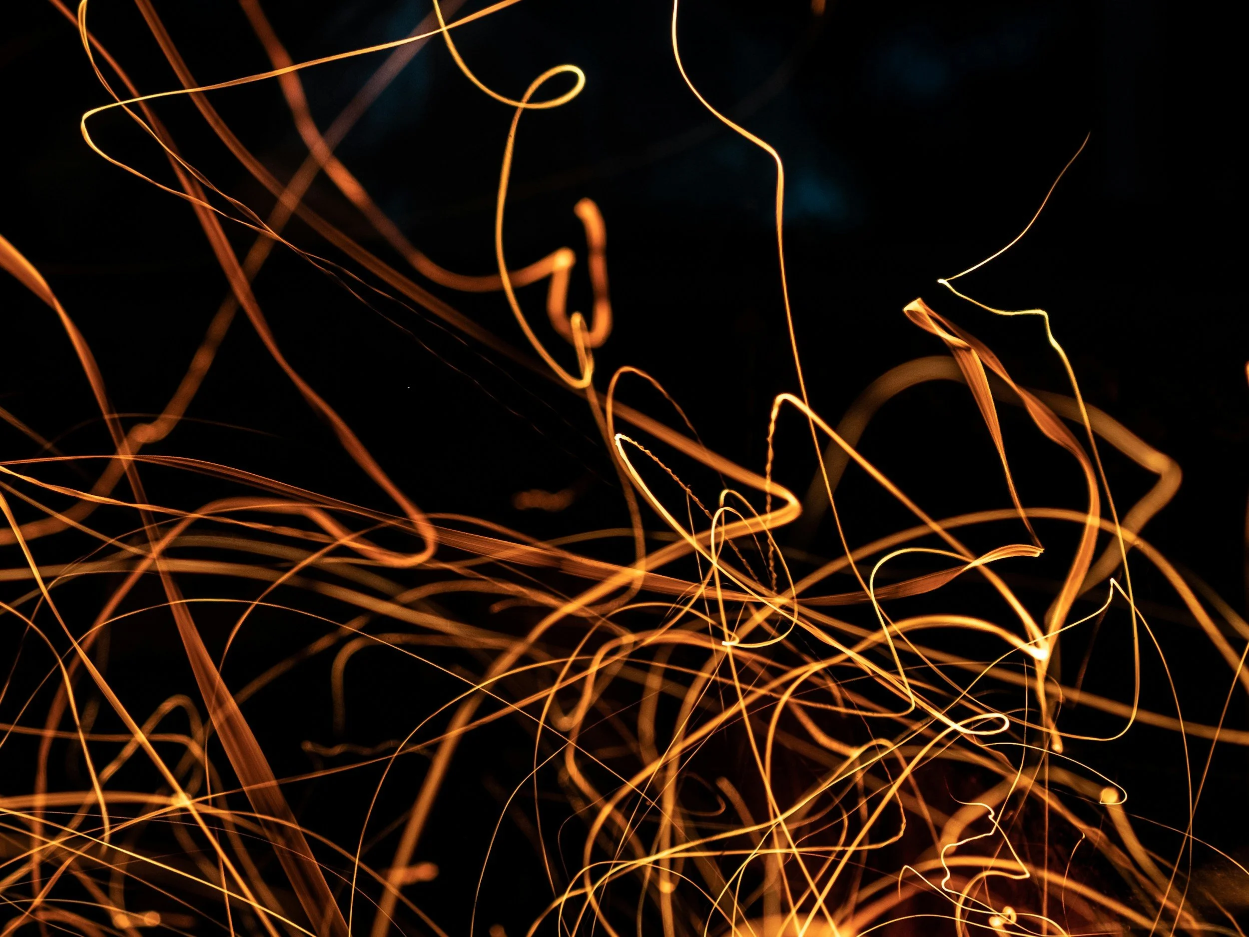 Close-up of glowing orange sparks and light trails against a dark background.