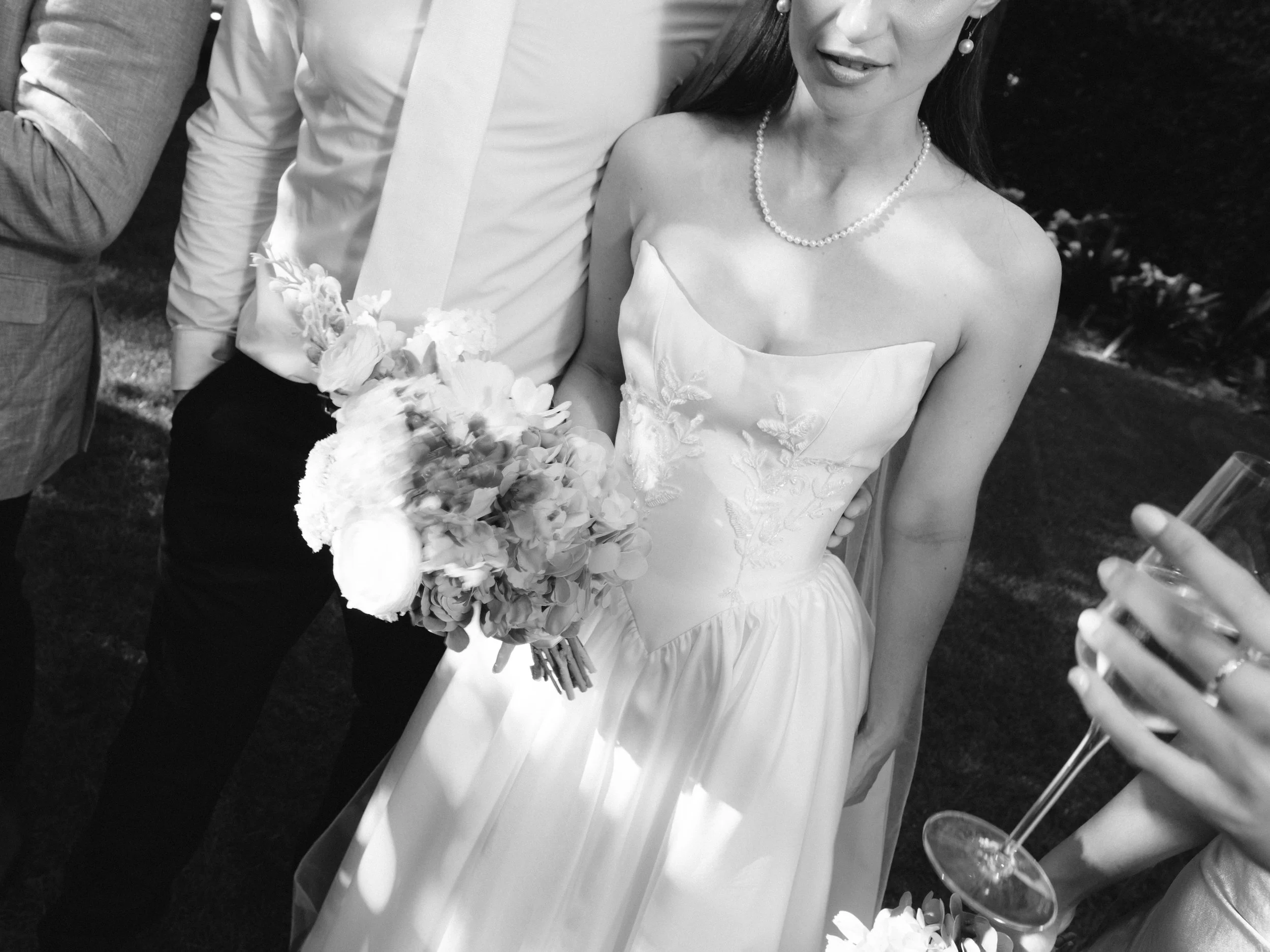 A woman in a wedding dress holding a bouquet of flowers, standing next to a man in formal attire at a wedding celebration.
