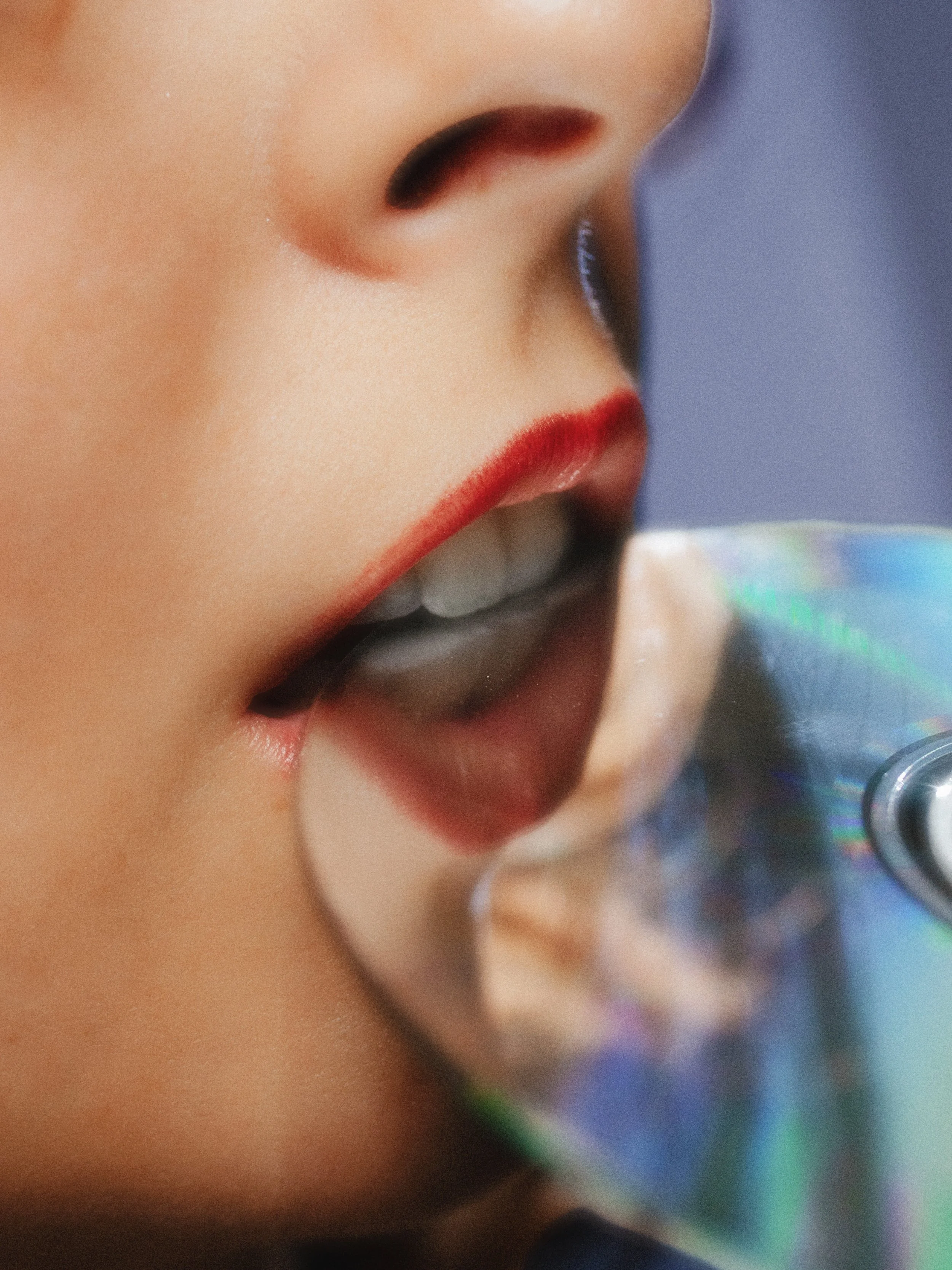 Close-up of a woman with red lipstick drinking from a can.