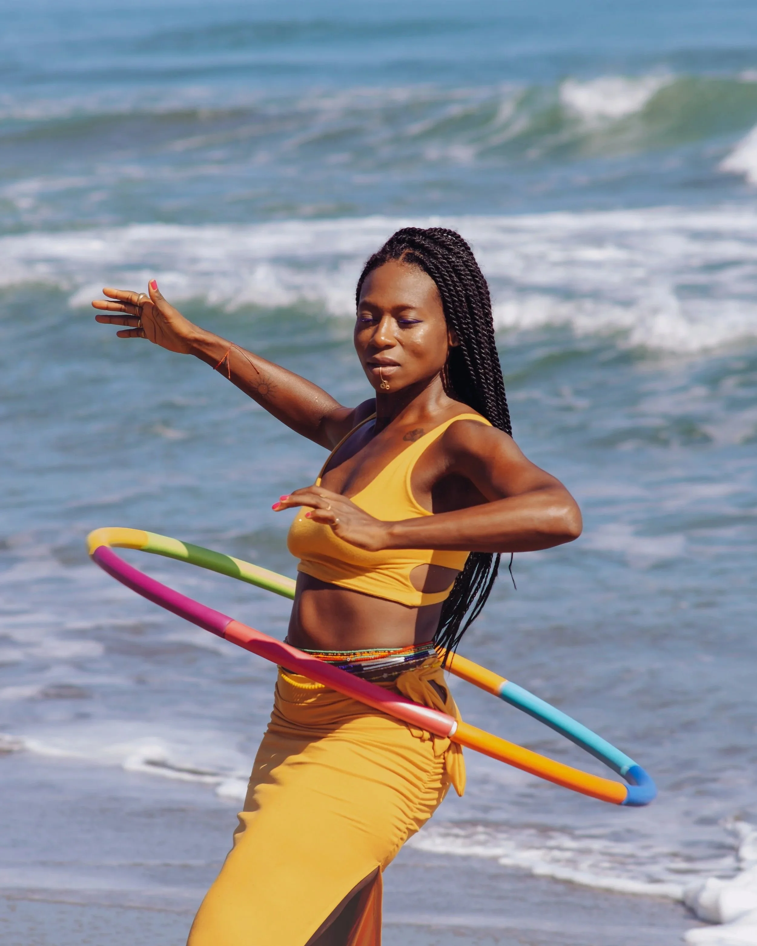 Black woman hula hooping joyfully on a beach in Costa Rica