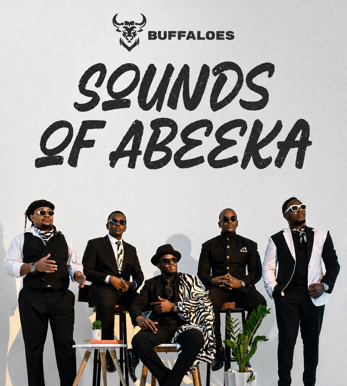 Five men dressed in black and white suits standing and sitting in front of a wall with the words "Sounds of Aseka" and a buffalo logo.