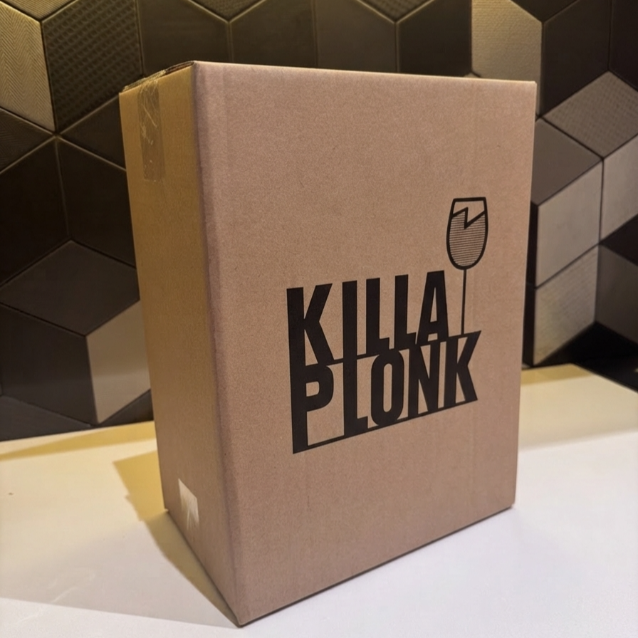 A cardboard box with the words "KILLA PLONK" printed on it along with a simple line drawing of a wine glass. The box is set against a geometric, black, tiled background.