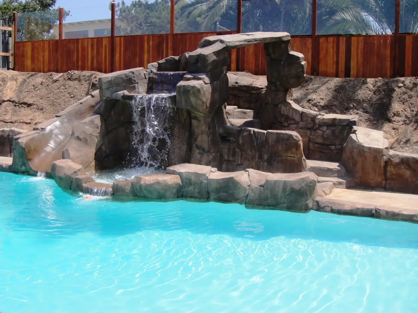 A swimming pool with a rock formation and a waterfall feature.