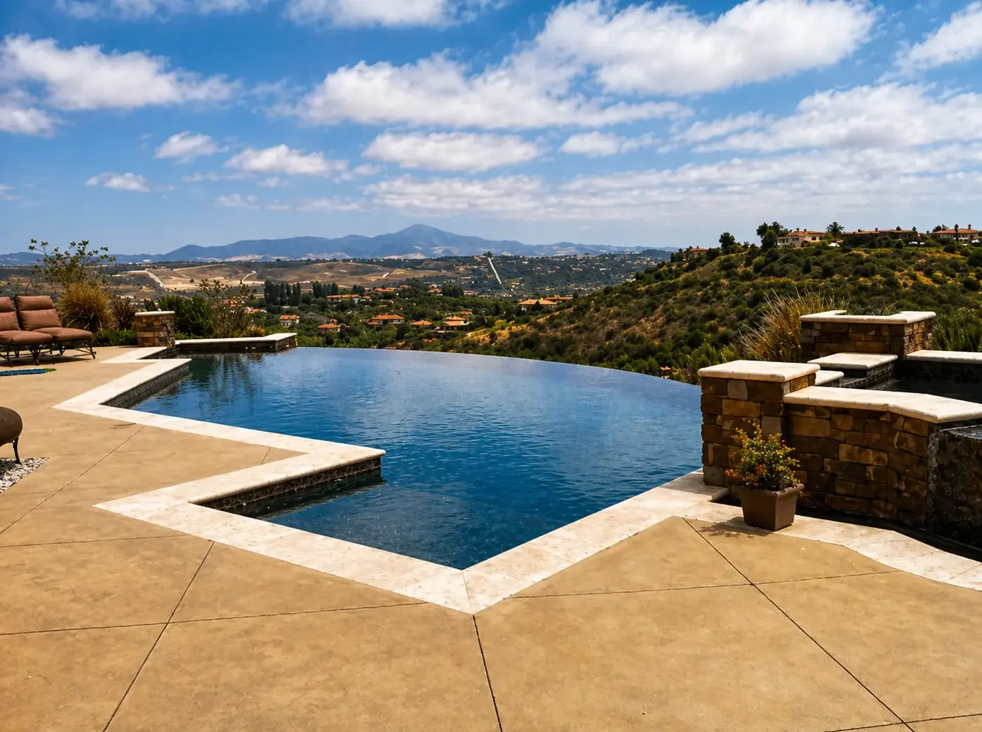 Luxury backyard with an infinity pool overlooking a hilly landscape under a partly cloudy sky.