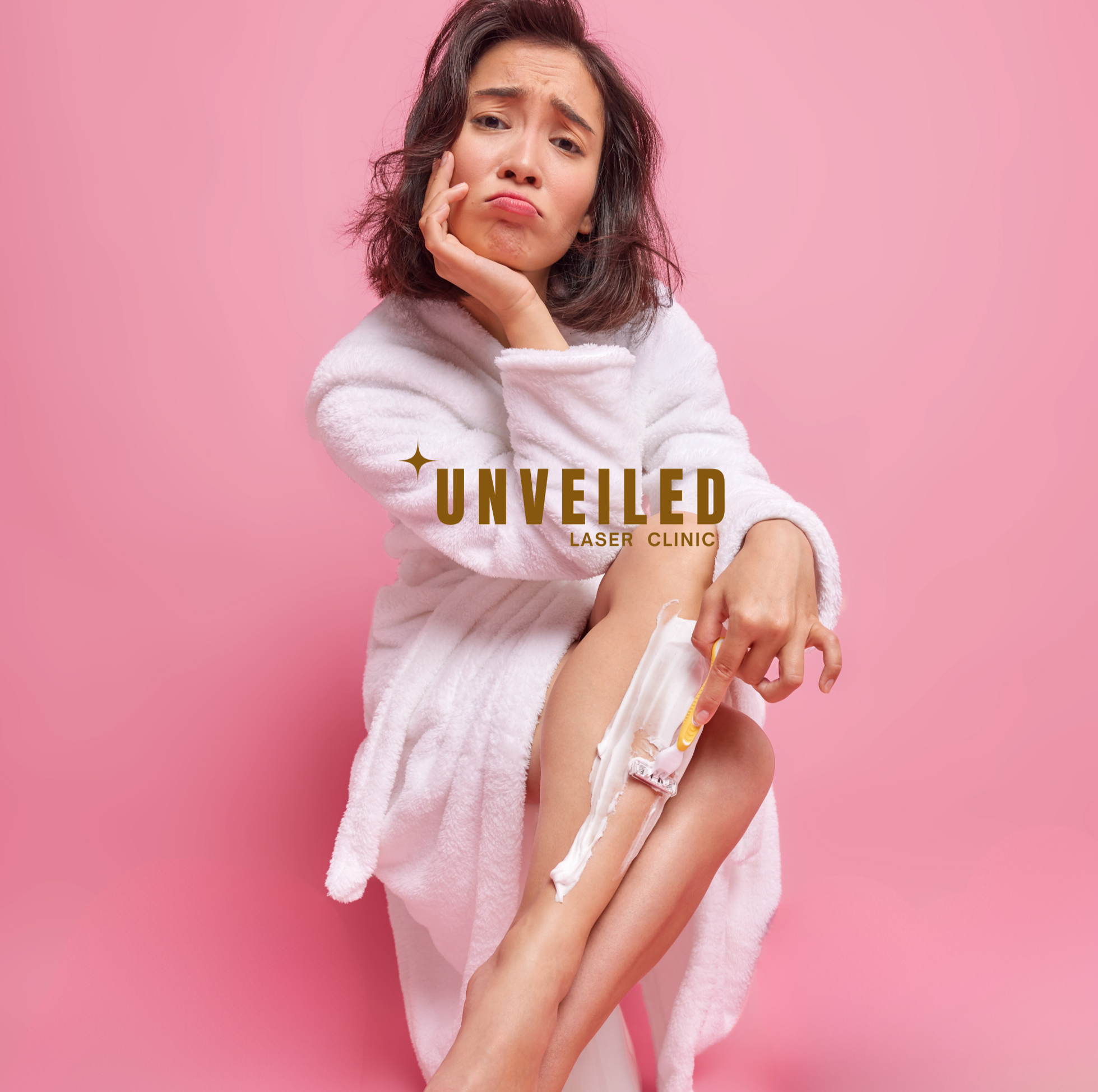 A woman with brown hair, wearing a white fluffy robe, sitting against a pink background, holding her leg with one hand, with shaving cream applied to her leg, looking concerned.
