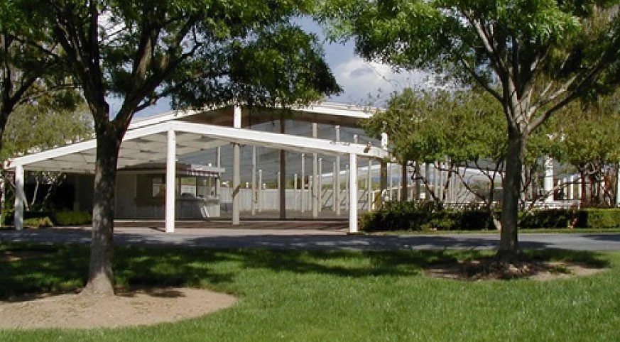 The Arbor Pavilion at Hecker Pass Outdoor Event Center showing a white roof and transparent side panels, surrounded by trees and grass, in a park or outdoor area.