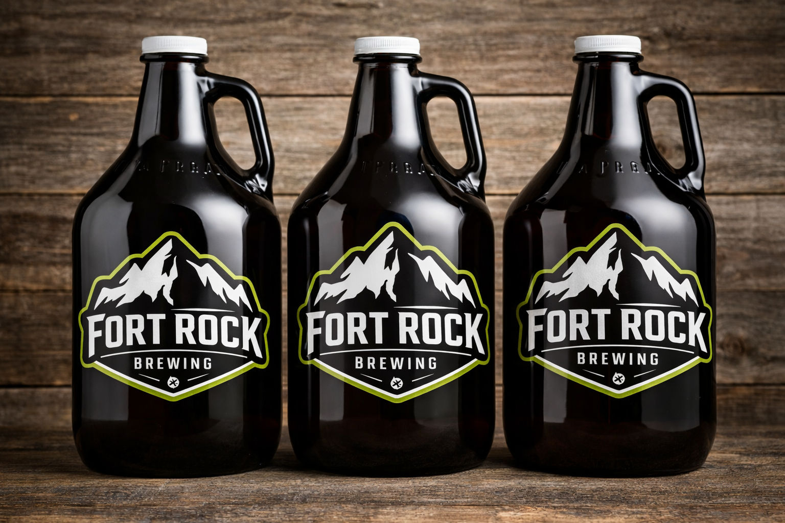 Three dark glass growlers with 'Fort Rock Brewing' labels featuring mountain graphics, placed on a wooden surface with a wooden background.