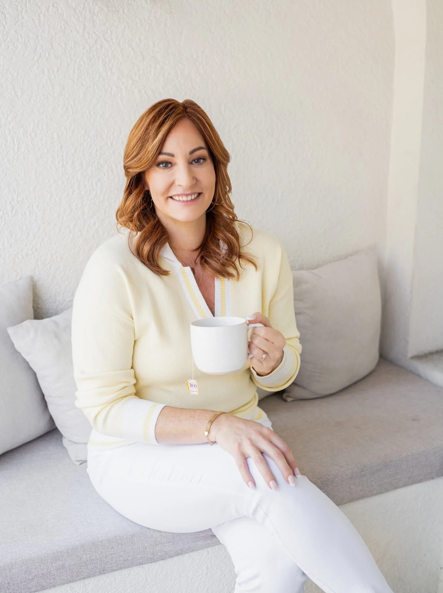 Registered dietitian, Torree seated in a light, neutral-toned room, smiling softly and holding a cup of tea