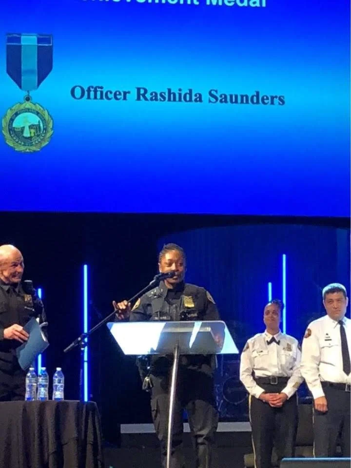 Rashida Saunders speaking on stage during a public safety awards ceremony.