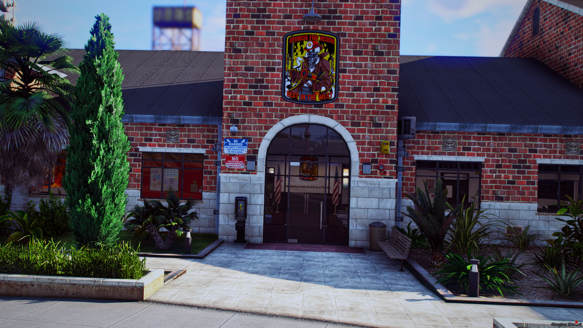 Front view of Georgia Fire Rescue station with brick exterior, featuring a colorful firefighter emblem above the entrance, surrounded by lush green plants and trees.