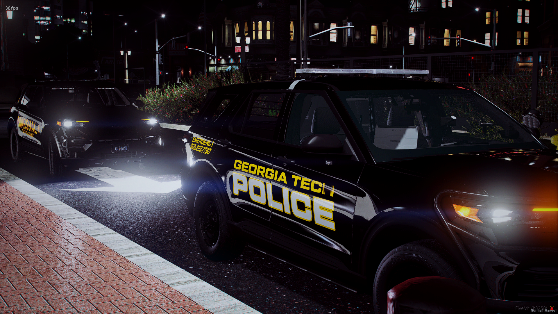 Two Georgia Tech police cars parked on a city street at night, with city lights and buildings in the background.