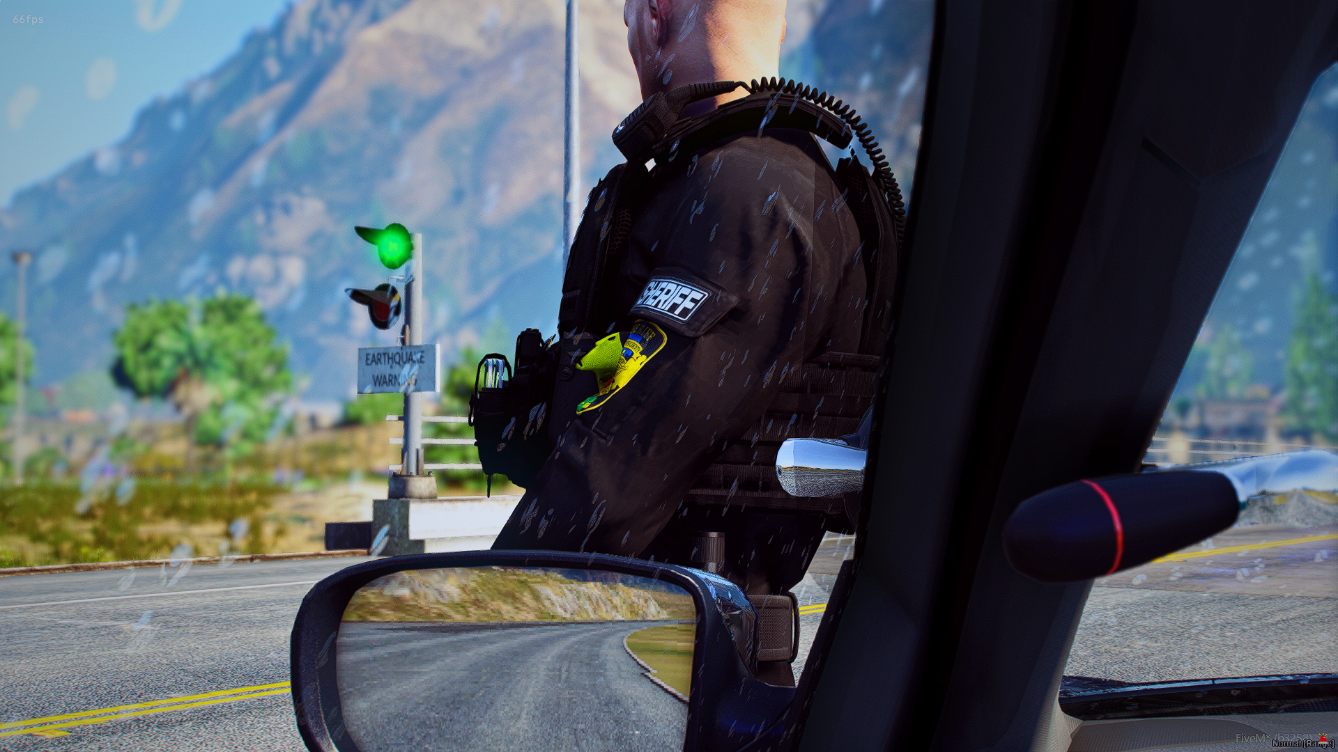 A police officer in uniform at a checkpoint, as seen from inside a vehicle, with mountains in the background and an earthquake warning sign.
