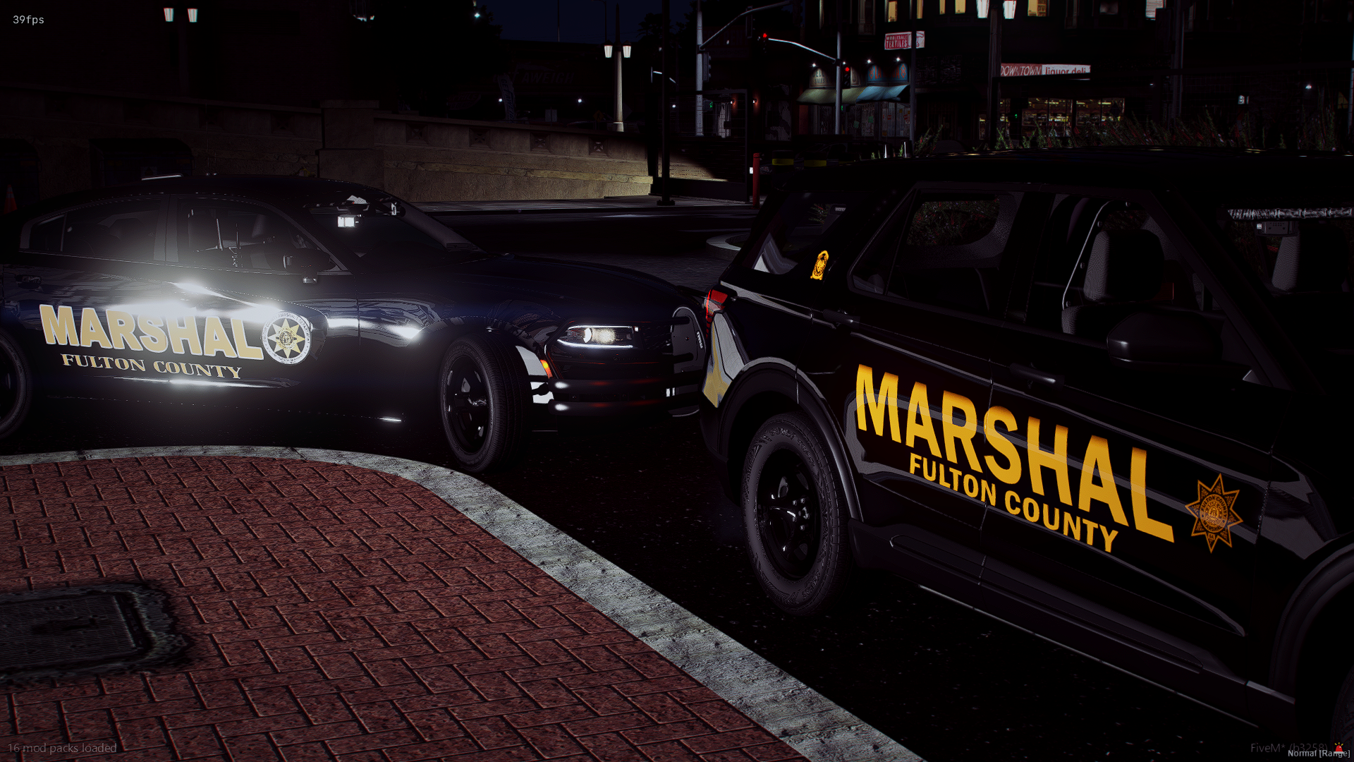Nighttime scene with two Fulton County Marshal vehicles, a black police car and a black SUV, parked on a city street near a brick crosswalk. The vehicles have bold yellow and white markings, with Fulton County Marshal logos visible.