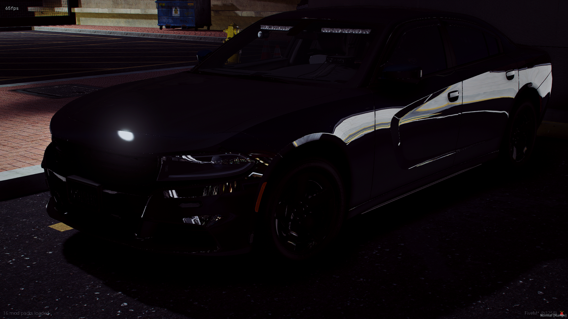 Black sedan car parked in a dimly lit parking lot at night