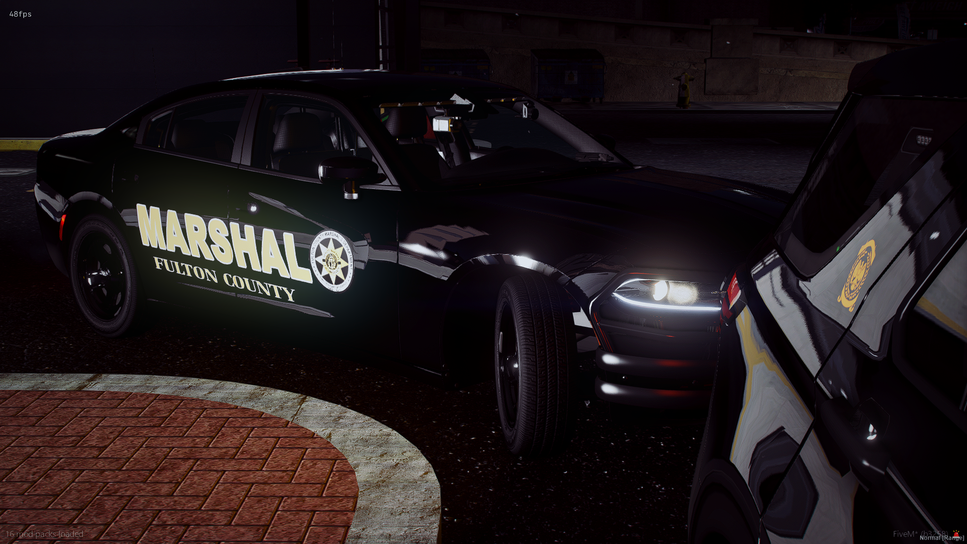 Nighttime scene showing a black Fulton County sheriff's police car with the word "MARSHAL" on the side, parked outdoors near a curb.