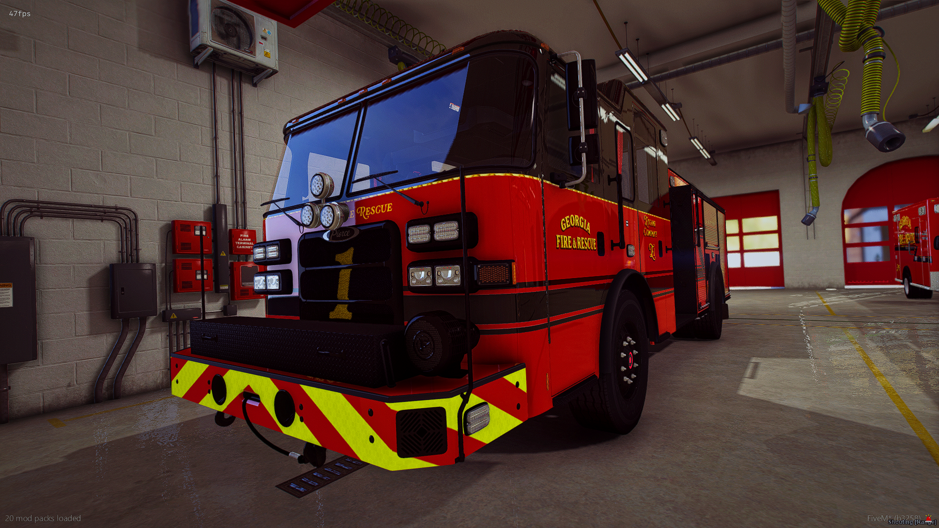 A red Georgia fire rescue truck inside a fire station garage, with yellow and red safety markings on the front bumper, and equipment and fire station doors in the background.